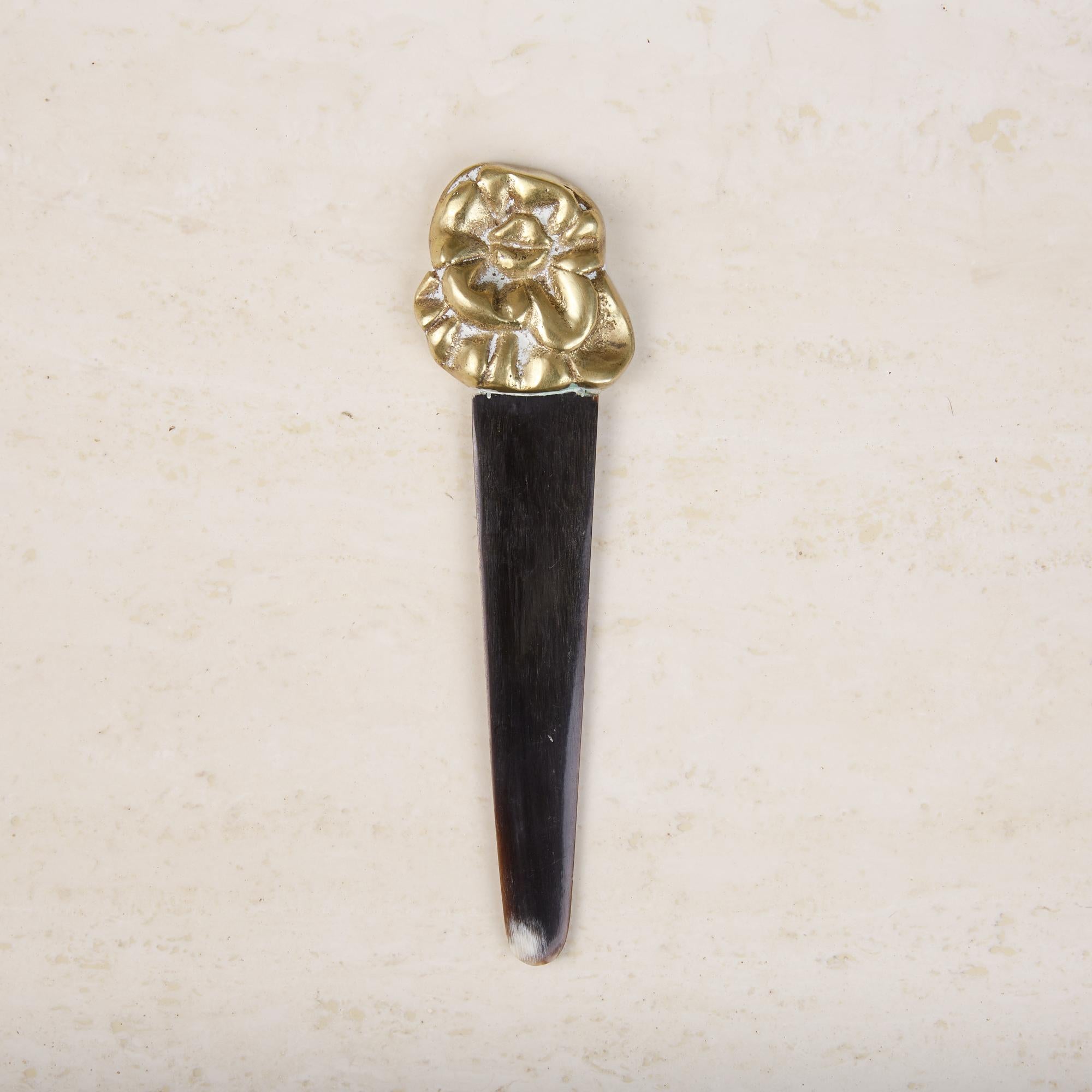 Cast bronze foot letter opener by Italian-Brazilian artist Pietrina Checcacci. The small weighted object features a patinated bronze floral shaped handle with a rounded horn blade. This quirky piece would be the perfect accent for any office