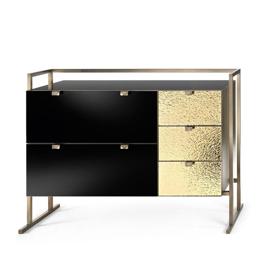 Chest of drawers Pietro with frame structure in metal
in burnished and antiqued brass finish. Structure and
inside drawers in matt varnished grey wood. Top and
2 drawers in black glass. 3 drawers in golden glass.
Sides in metal in burnished and