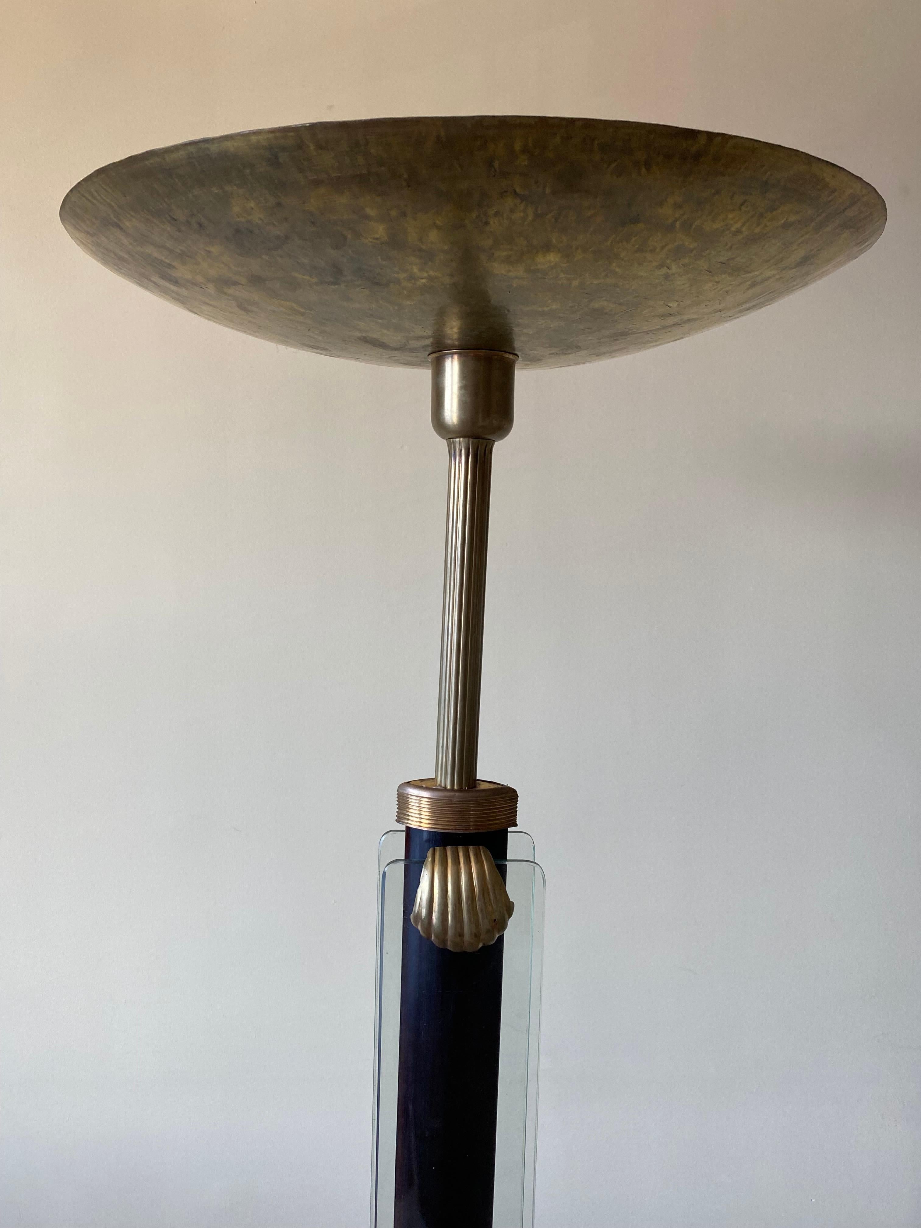 Beautifully patinated brass torchiere floor lamp attributed to Pietro Chiesa for Fontana Arte, circa 1930s.

Glass panels run along the center column. Fastened to the ebonized wood with washer/nuts and covered in decorative brass shell clips.
