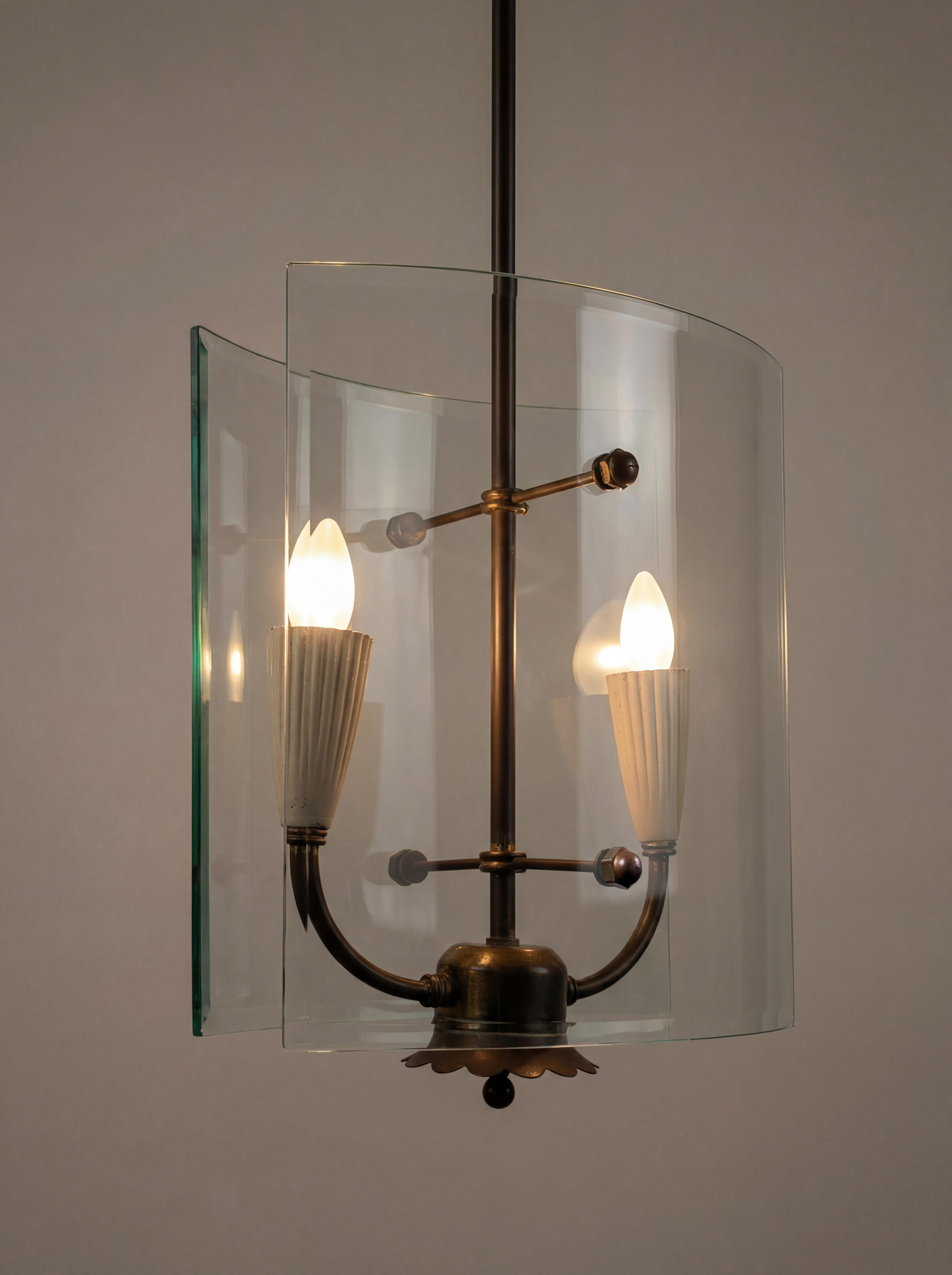 Pietro Chiesa designed this refined curved glass and brass pendant light for Fontana Arte in Italy during the 1940s. The fixture features a central brass stem supporting two vertical sheets of transparent curved glass that shield the illumination