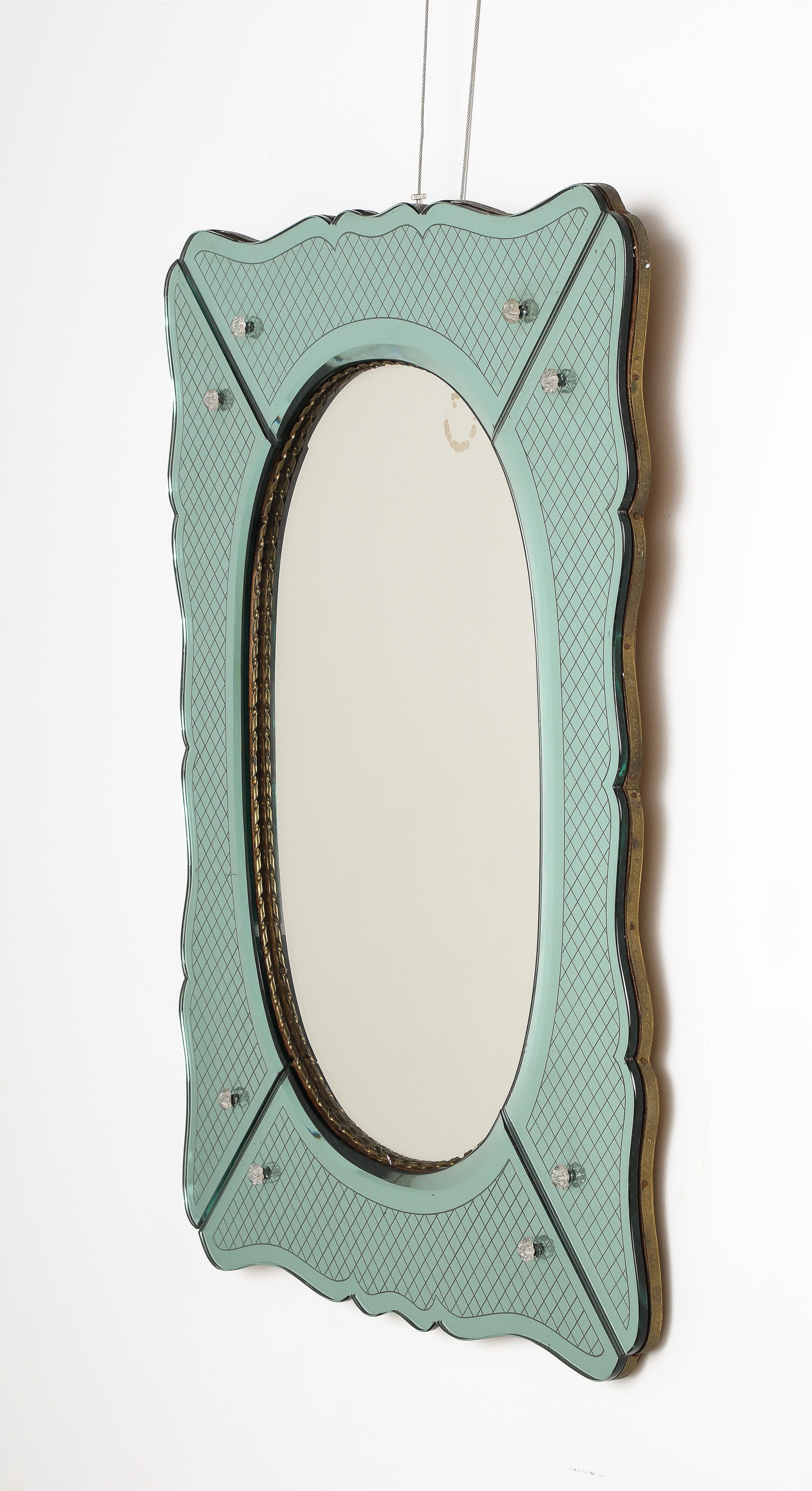 A Pietro Chiesa for Fontana Arte etched glass mirror in a stunning aqua color. The scalloped shaped form is segmented with etched glass motif and decorated with crystal rosettes.  The inner oval mirror plate is surrounded by a braided brass molded