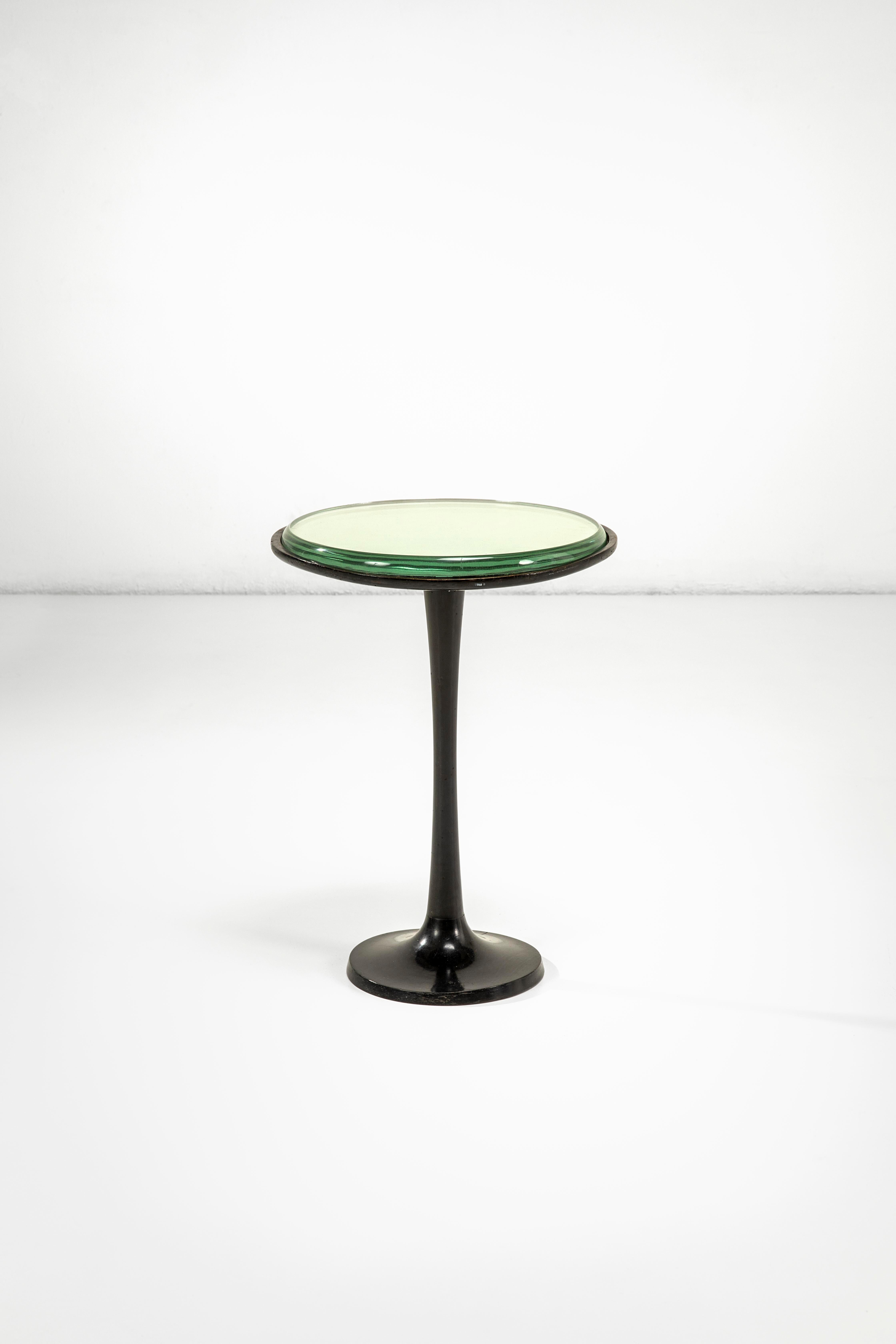 This elegant occasional table with an ebonized wood structure and a beveled mirrored crystal top is delicate, discreet, and with sinuous lines both in terms of the structure itself and the finishes such as the magnificent grinding of the crystal.