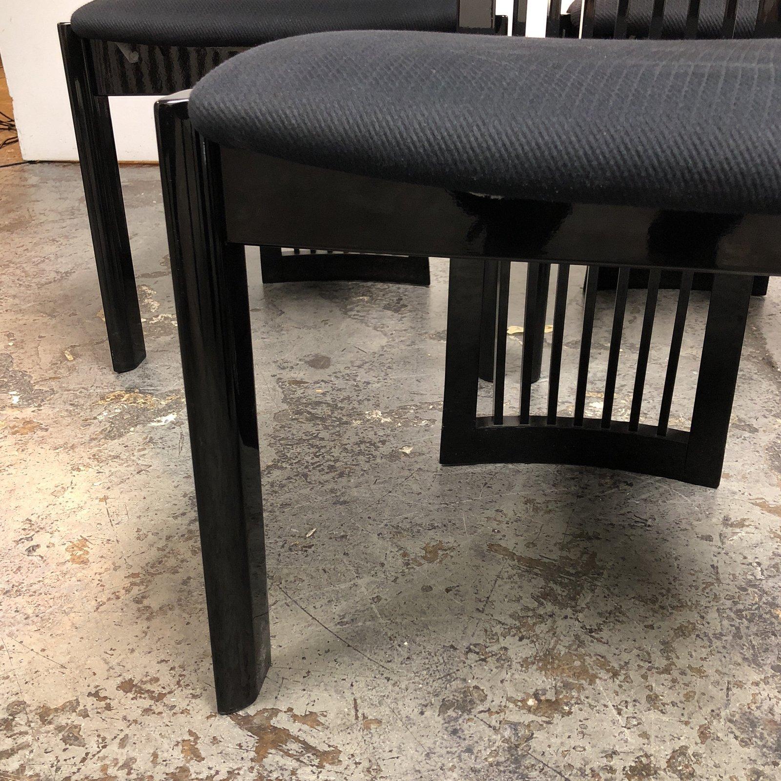 A set of eight Pietro Costantini dining chairs sold by Ello Furniture in black on black. Minor wear from sun exposure on fabric. Shades of black define these pieces; black matte fabric cushions lightly contrast the glassy onyx lacquer finish on the