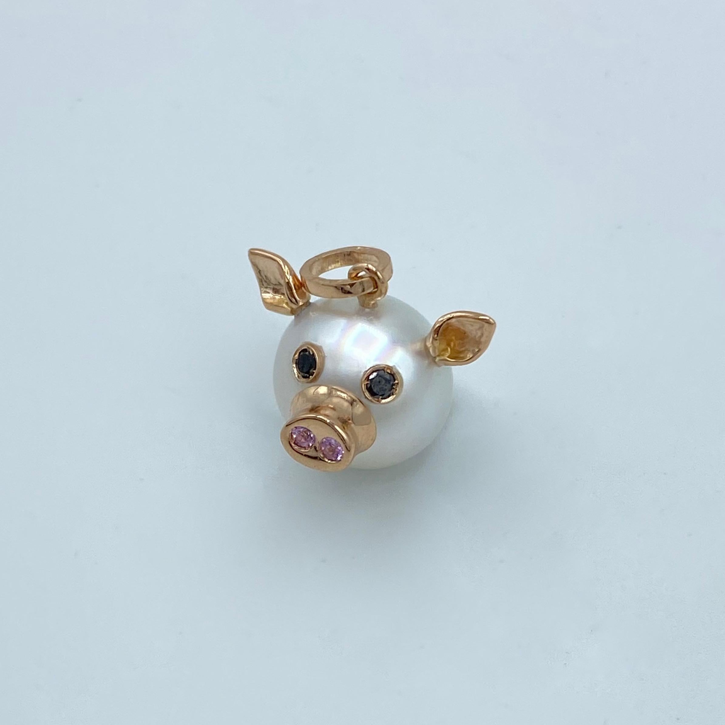This nice pendant is made with a button Australian pearl. 
It has two ears, two eyes with black diamonds.  
In the holes of its nose there are two pink sapphires encrusted, in total ct 0.03.
All the particulars made in red gold.
The diamonds are in