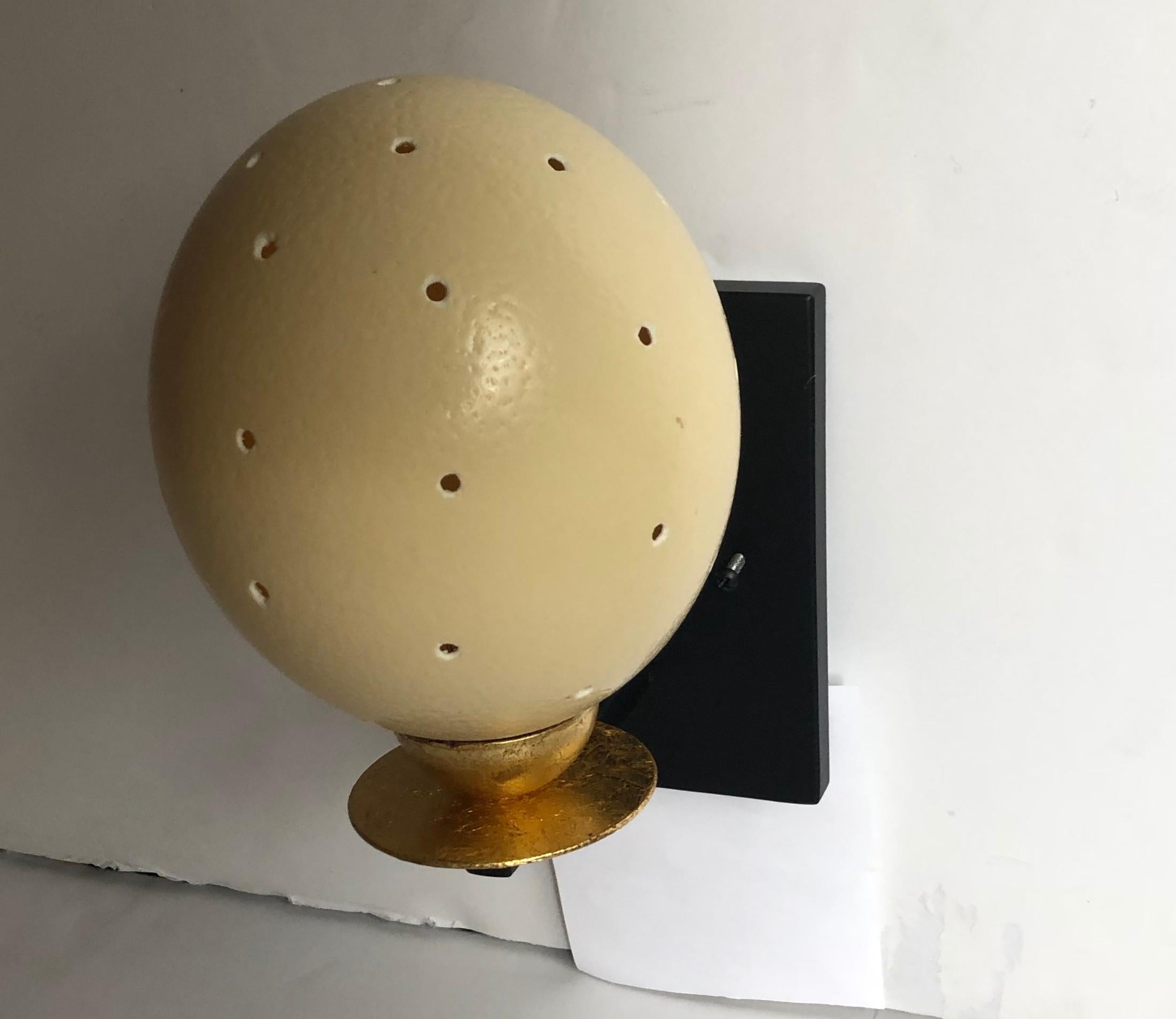 Das Licht dieser einzigartigen Wandleuchter mit ihrem schlichten, klaren Design ist warm und faszinierend. Die blattgoldenen Akzente auf den Lichtern passen gut zu den Eierschalen und der schwarzen Emaille-Rückplatte. Perfekte Akzentbeleuchtung. Die