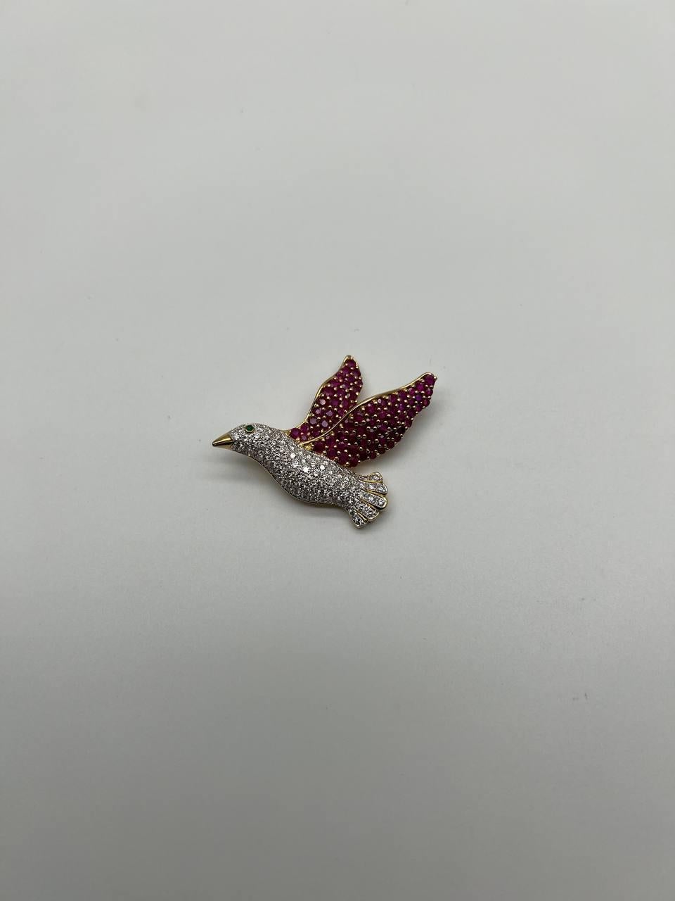 Experience the refined beauty of this exquisite pigeon bird brooch.

Crafted with meticulous attention to detail, the brooch features a bird in flight, adorned with shimmering rubies and diamonds.

The wings are encrusted with vibrant red pink