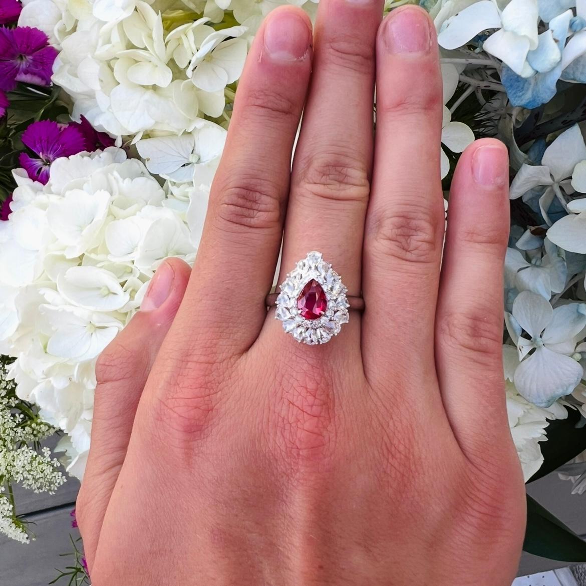 Es gibt rote Rubine, und es gibt taubenblutrote Rubine. Dieser wunderschöne Ring aus 18-karätigem Weißgold zeigt einen lebhaften, farbintensiven birnenförmigen Rubin mit einem Gewicht von 1,02 Karat, umrahmt von runden birnenförmigen Diamanten im