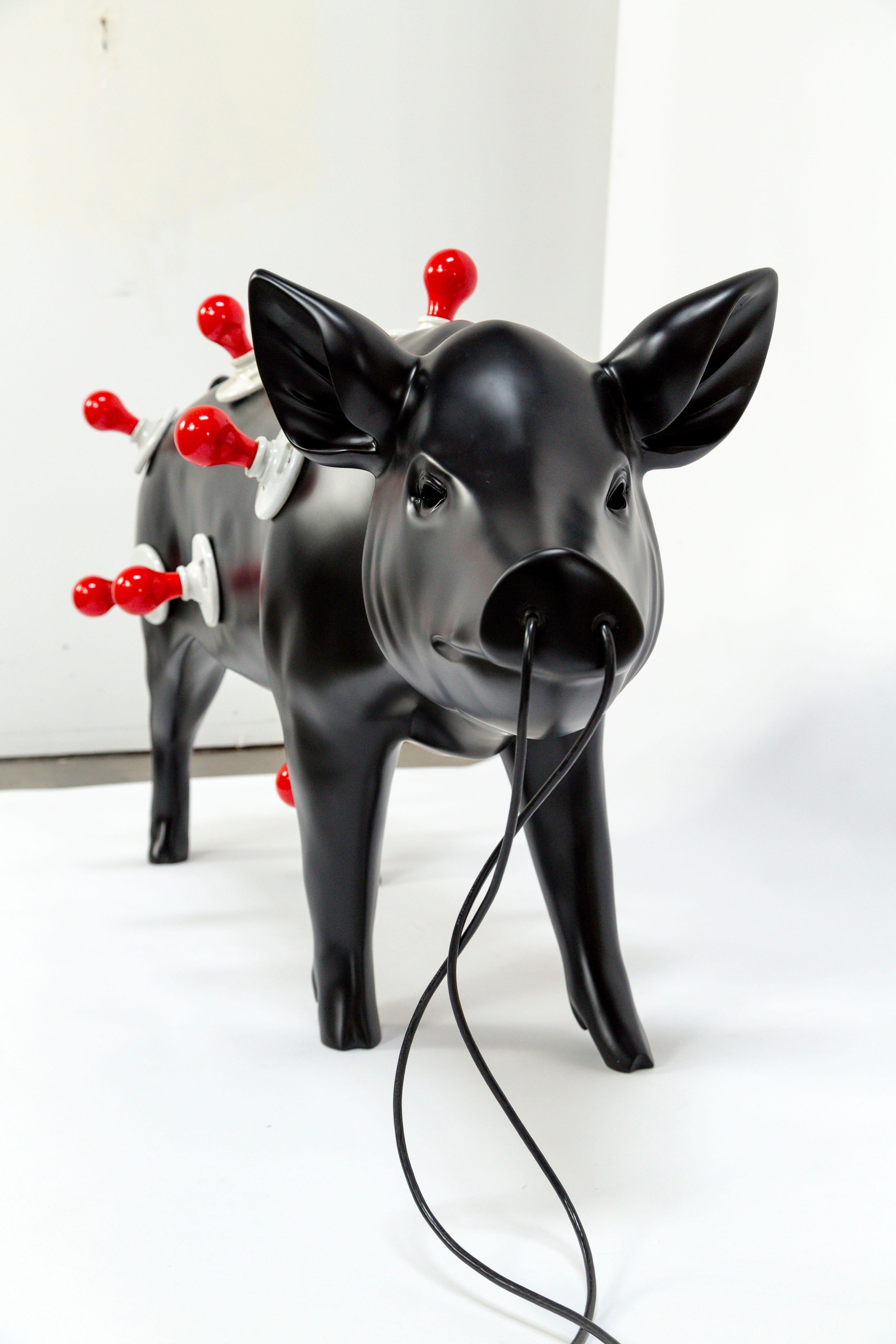 This eccentric object of sculptural lighting has a sleek, satin black finish with 13 medium base porcelain sockets, and two long cords from the animal's nose with inline switches. Piggy is a collaborative work which involved several artisans. The
