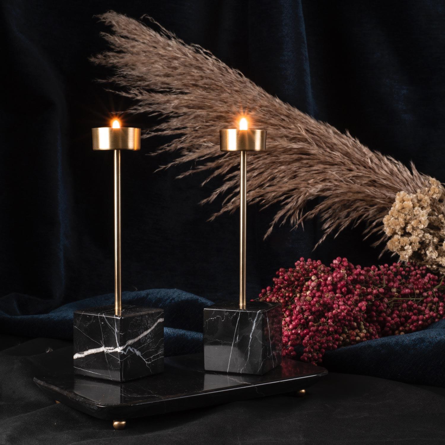 Indulge in the exquisite beauty of the Yunta Tealight Candle Holder, a true masterpiece of artisanal craftsmanship. This decorative and luxurious piece combines a hand-carved marble base with two brushed brass poles, creating a visually stunning
