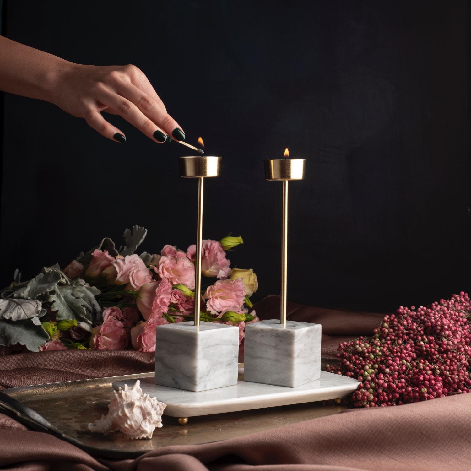 Indulge in the exquisite beauty of the Yunta Tealight Candle Holder, a true masterpiece of artisanal craftsmanship. This decorative and luxurious piece combines a hand-carved marble base with two brushed brass poles, creating a visually stunning