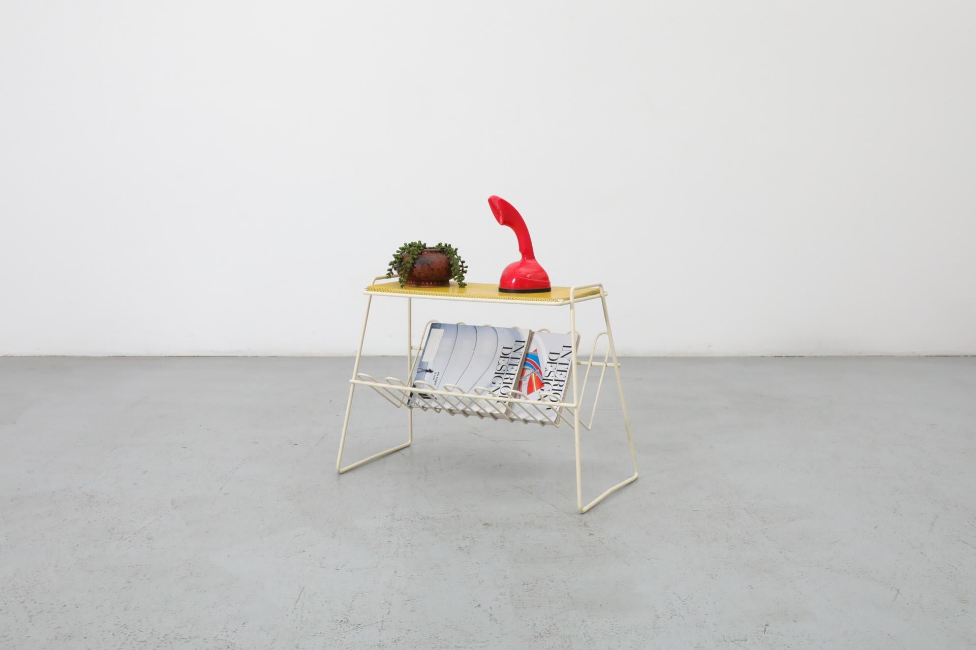 1960's Pilastro attributed yellow perforated telephone table with white enameled metal wire frame and integrated magazine rack. In original condition with visible wear, including enamel loss and chips and scratches. Wear is consistent with its age