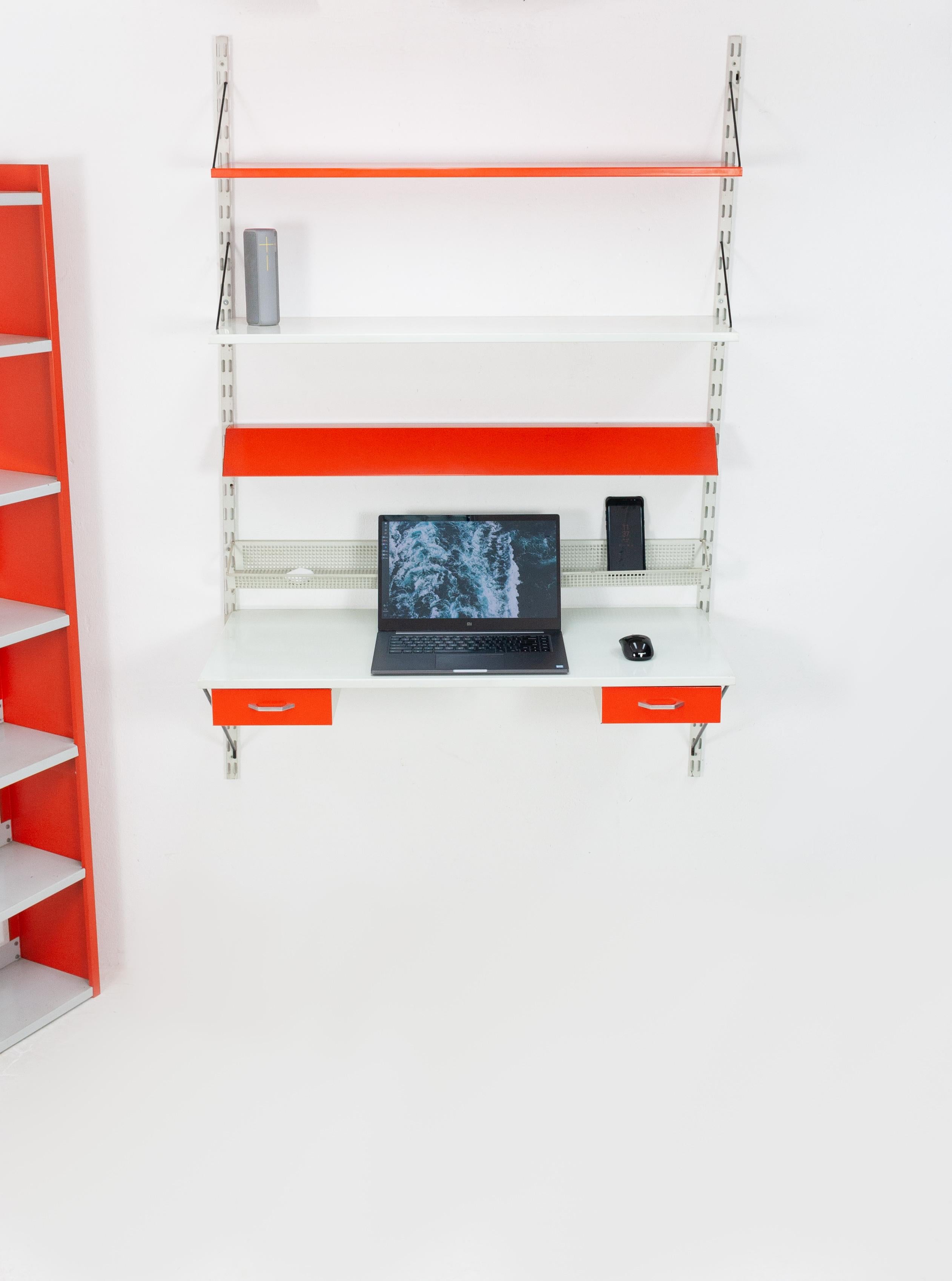 Pilastro modulair wall desk and bookcase. Matching set. Design Tjerk Rijenga for Pilastro, Holland, 1960s.
Orange with grey metal color. The desk contents two drawers. Comes with lighting, two e27 bulbs. And a perforated tray for all kinds of