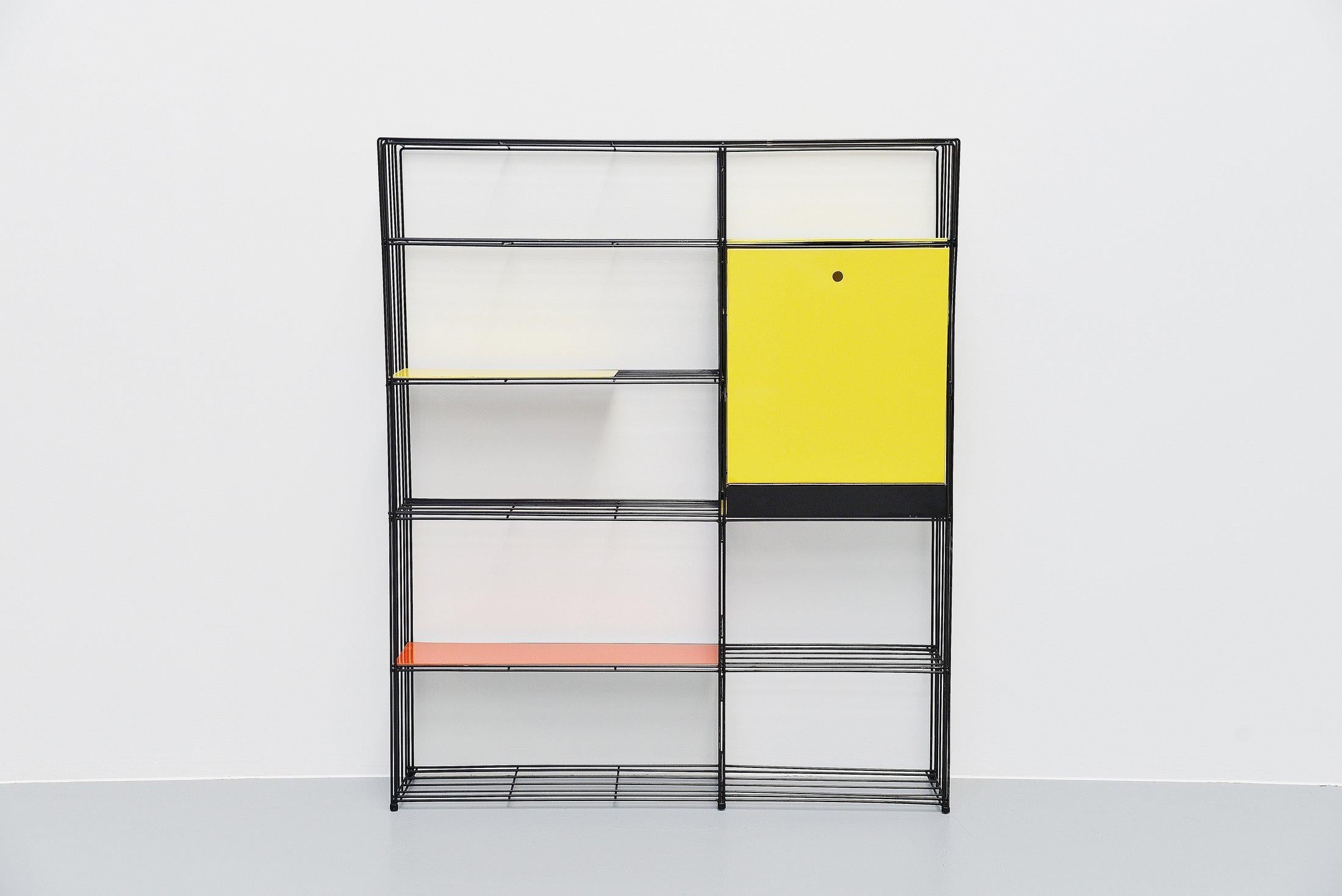 This very nice bookcase / room divider designed by Tjerk Reijenga and manufacrured by Pilastro , Holland 1960. This black wire frame divider is complete with the original colored shelves which are often missing or replaced.  This example has