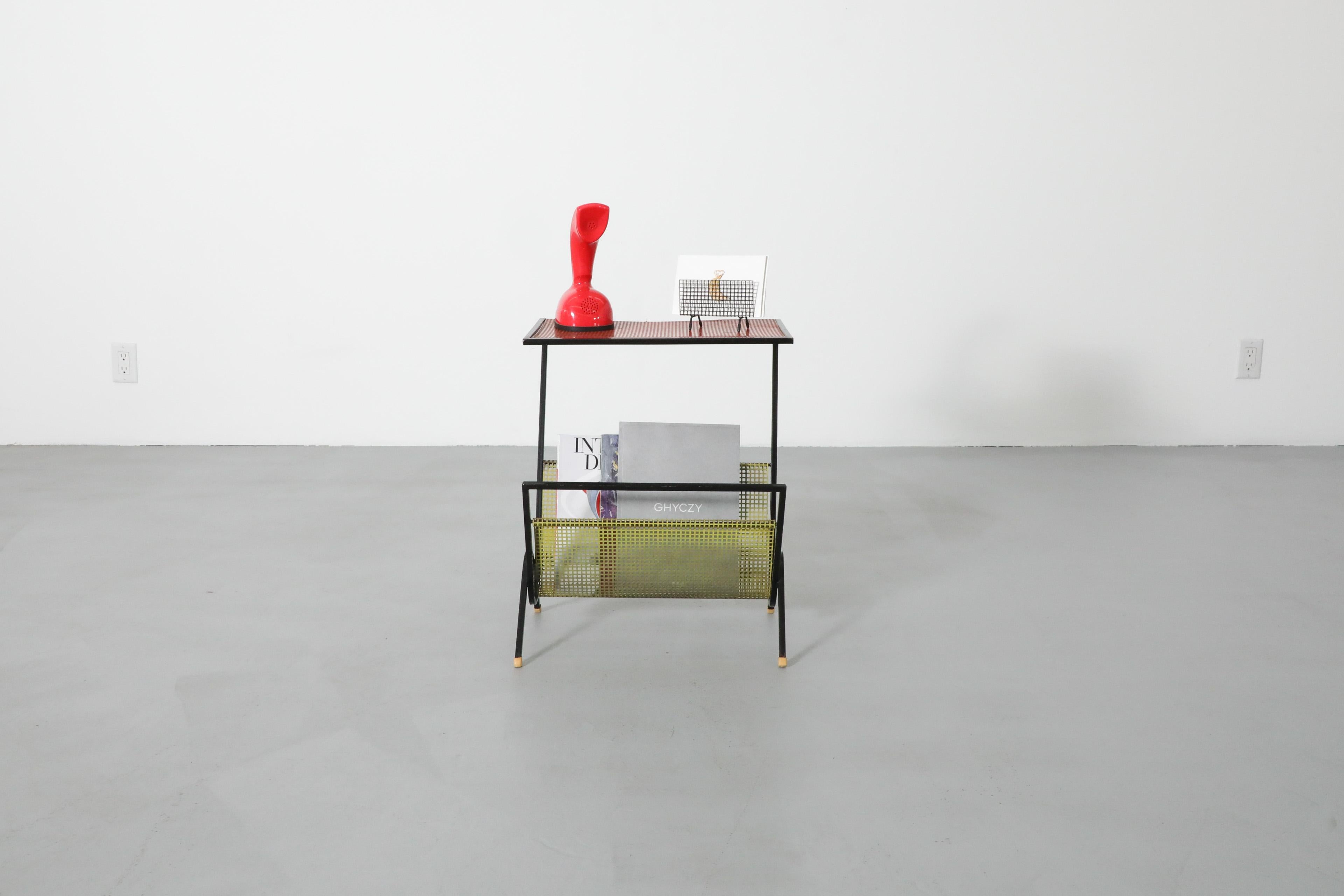 Dutch Mid-Century, Pilastro style telephone or side table with multi-colored perforated metal and black enameled metal frame. A versatile, industrial style table with red and yellow perforated top and magazine rack with plastic foot caps. In