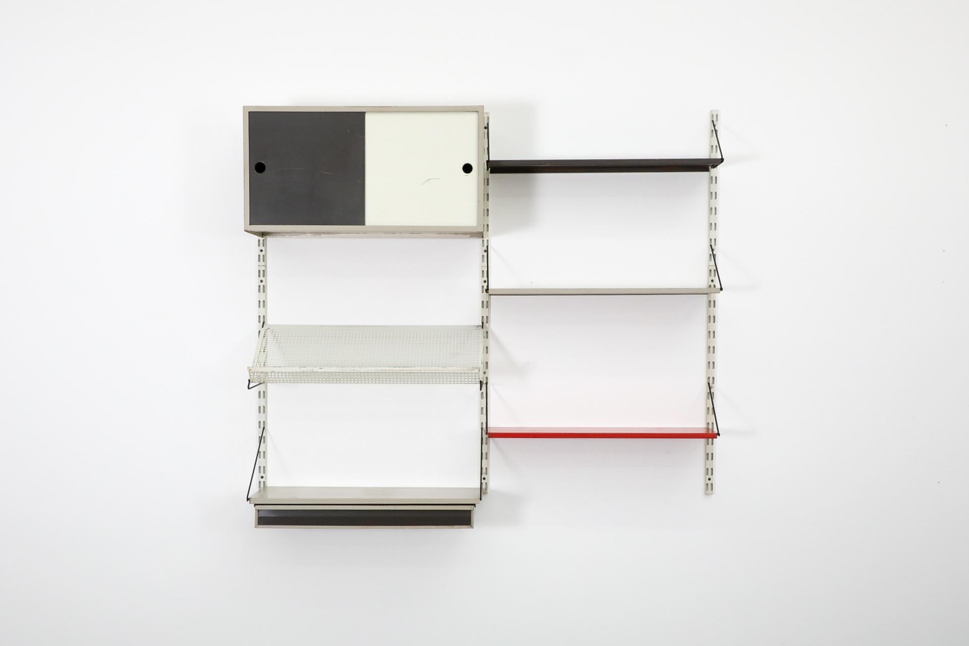 Dutch Mid-Century, Pilastro wall unit with desk, cabinet, and perforated rack. This unit features a gray enameled desk, black and white metal cabinet with enameled sliding doors and white perforated magazine display. In the 1950s and 1960s,