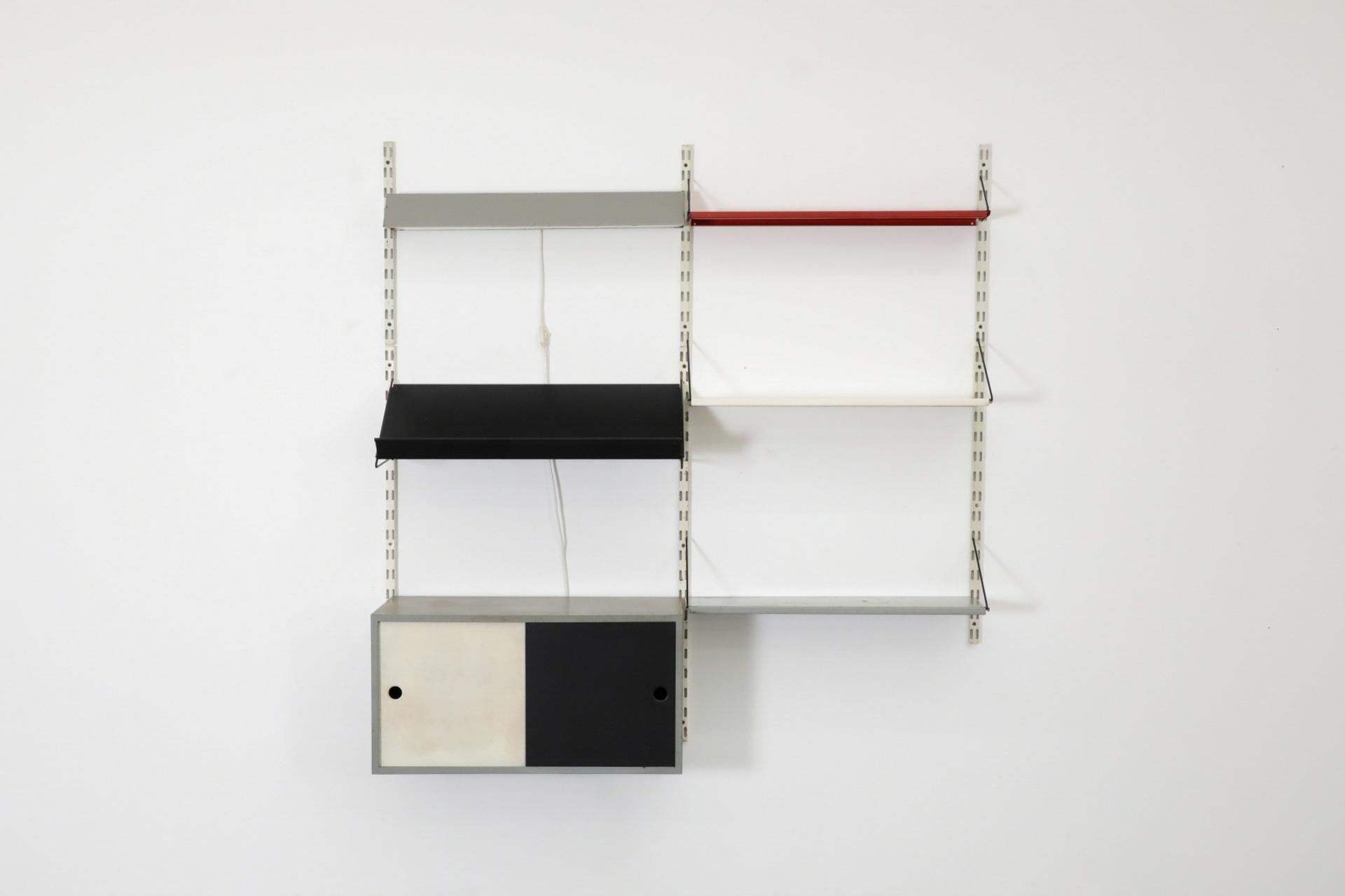 Estantería de pared de metal esmaltado Pilastro holandés de mediados de siglo. Este mueble dispone de un armario metálico con puertas correderas esmaltadas en blanco y negro, una luz gris lineal, un estante negro expositor de revistas a la