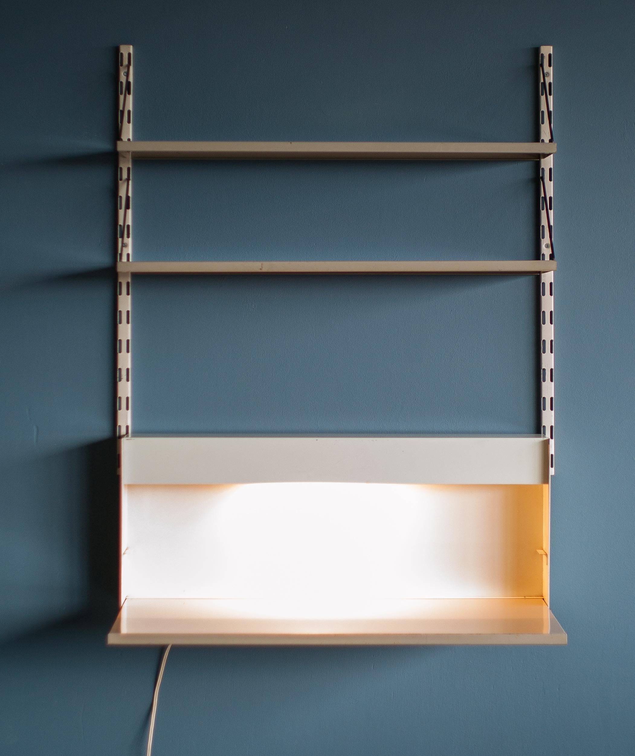 Sistema a parete minimalista progettato da Reijenga per Pilastro, Paesi Bassi.
Due ripiani e una scrivania a ribalta di colore beige.
La scrivania ha una luce nascosta dietro il pannello frontale.
Design salvaspazio Mid Century Modern, perfetto per