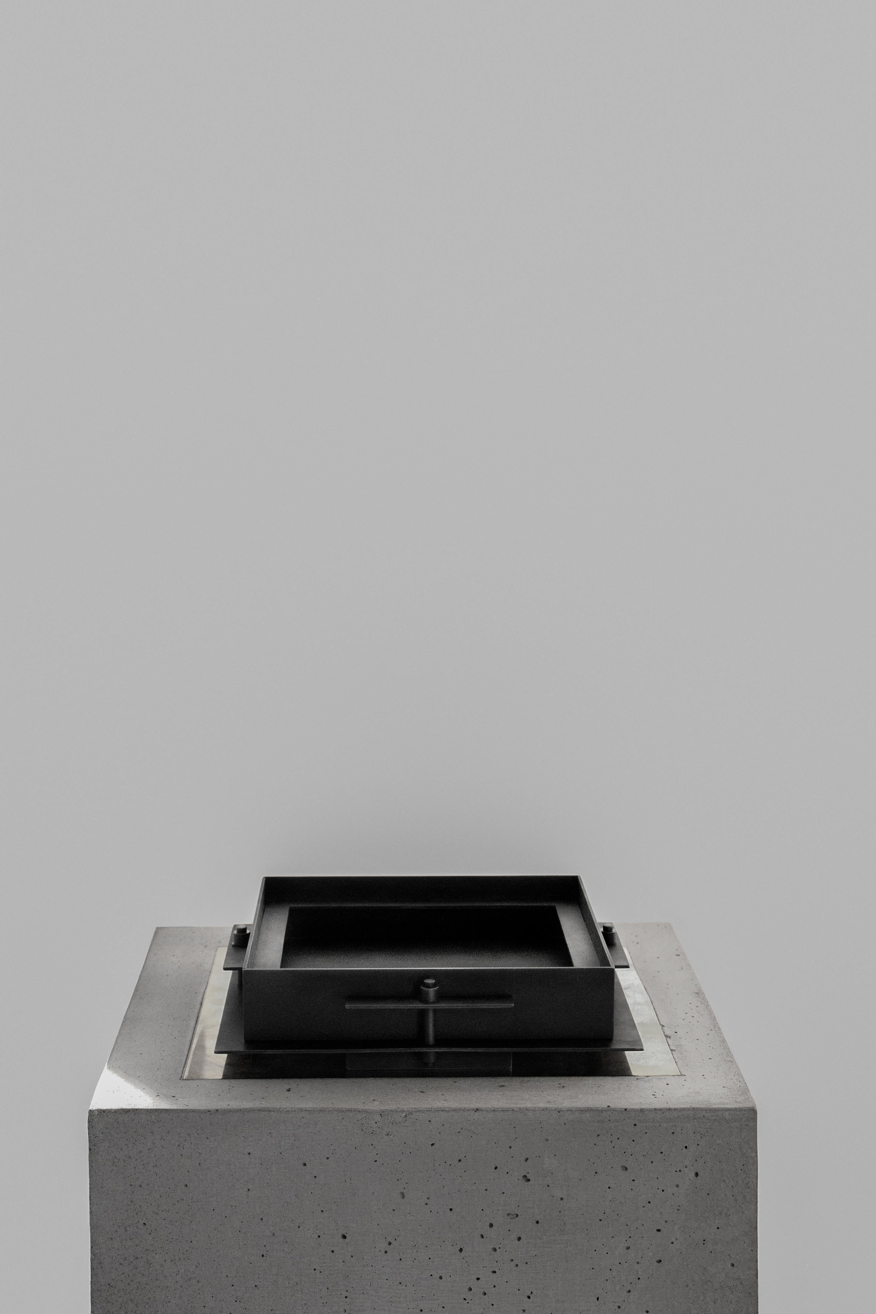 Pilier small tray by Sizar Alexis
Unique Signed Piece
Dimensions: Length 23 x width 23 x height 6 cm
Materials: Blackened steel, ox leather 

A series of boldly sculpted furnitures and objects, an
appreciation of the raw metal feel and