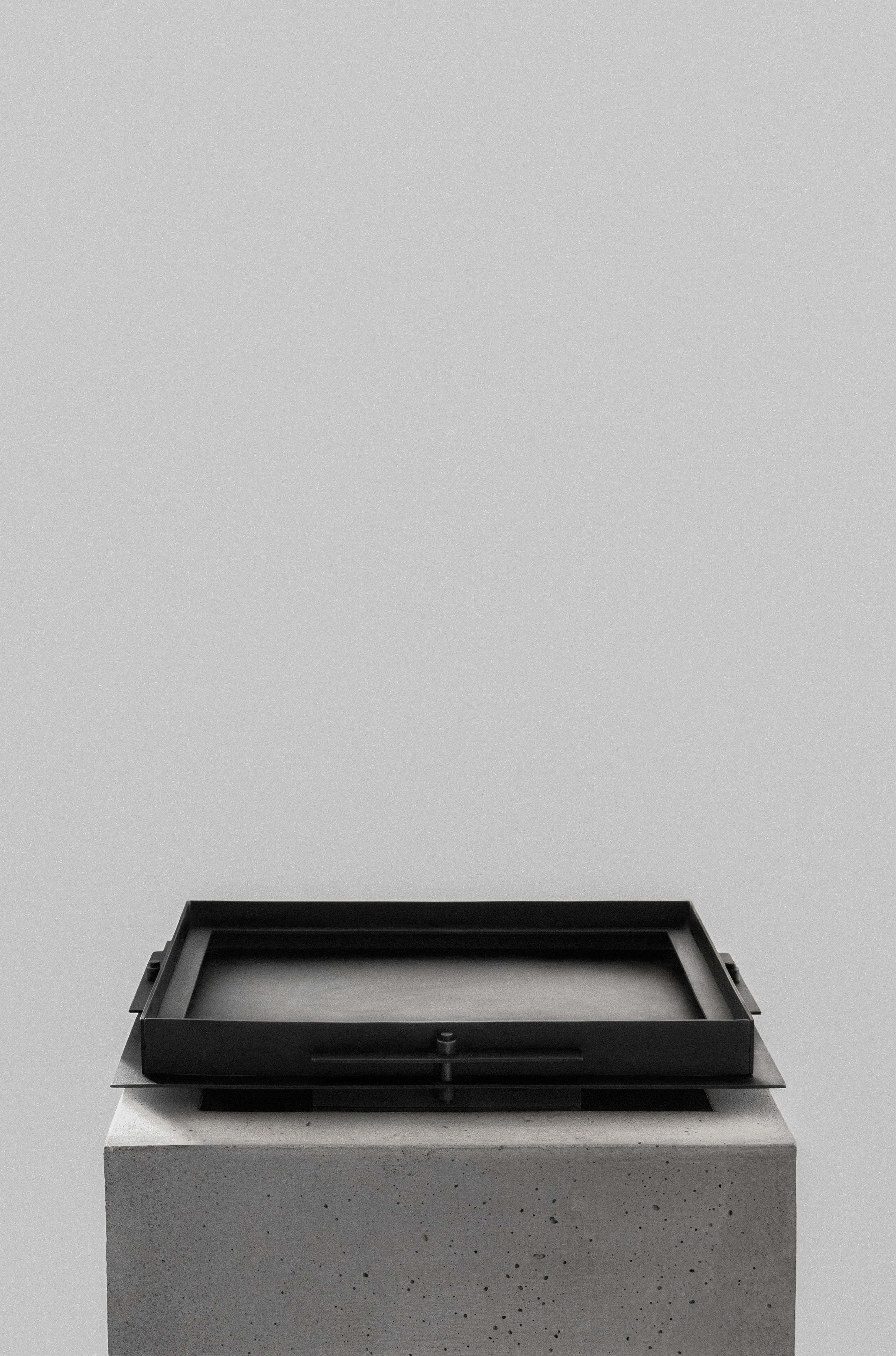 Pilier steel tray by Sizar Alexis
Unique signed piece
Dimensions: Length 35 x width 28 x height 4.5 cm
Materials: Blackened steel, ox leather

A series of boldly sculpted furnitures and objects, an
appreciation of the raw metal feel and