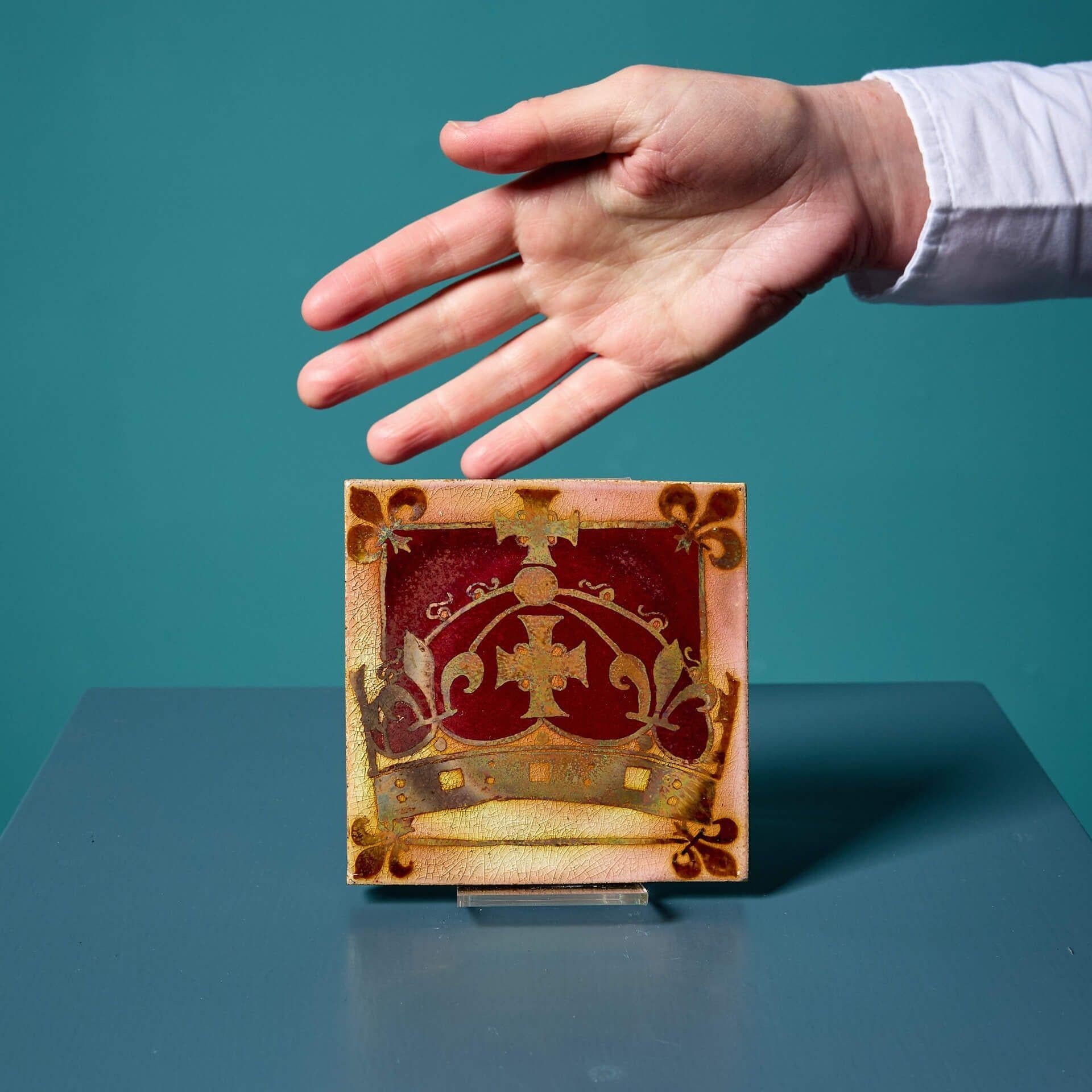 Eine sehr gut erhaltene antike 4-Zoll-Lüsterfliese, die der Pilkington's Tile and Pottery Co. zugeschrieben wird und mit einer heraldischen Krone verziert ist; eine von zwei ähnlichen, die wir zum Verkauf haben.

Diese antike 4-Zoll-Sammlerfliese