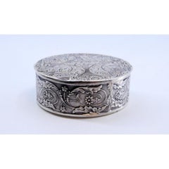 Pill box in embossed silver with round floral motifs and hinged lid