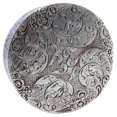 Pill box in embossed silver with round floral motifs and hinged lid