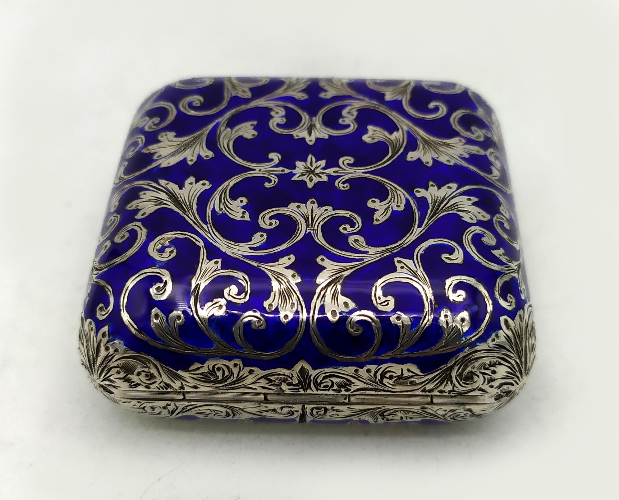 
 Gran pastillero cuadrado de bolsillo con esquinas y lados redondeados, de plata de ley 925/1000 con grabado a mano muy fino de estilo barroco, esmaltado al fuego. Tamaño cm. 5 x 5 x 2. Peso g. 75. Diseñada por Franco Salimbeni en 1974 y producida