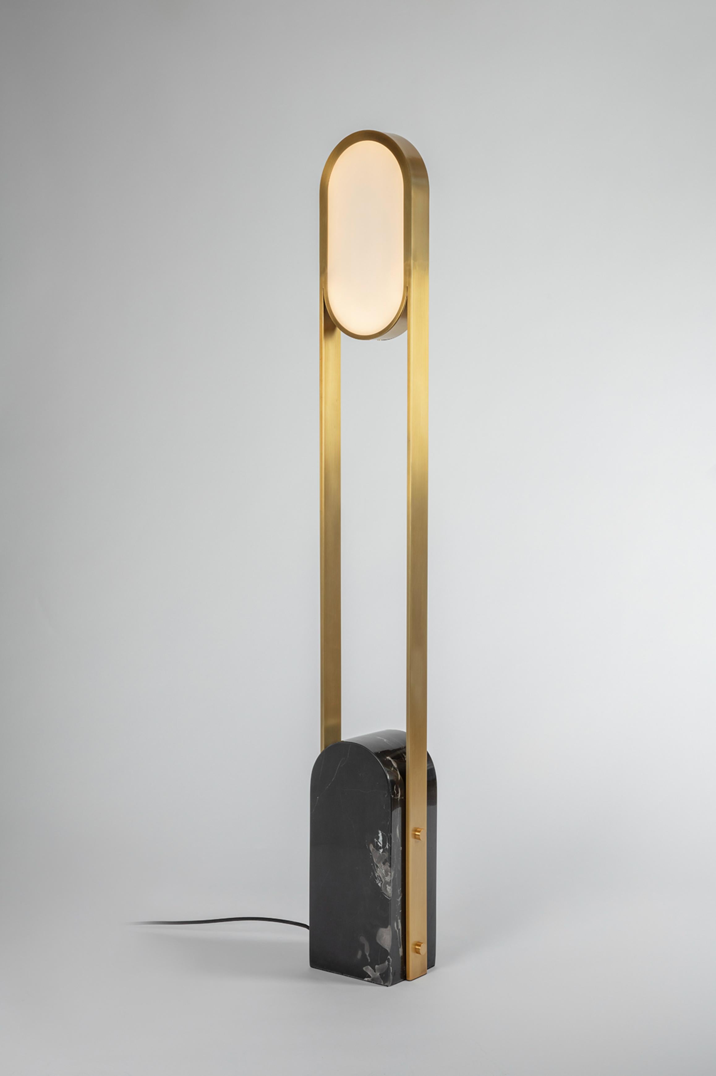 Pill floor lamp by square in circle.
Dimensions: D 14 x W 20 x H 145 cm.
Materials: brushed brass / black marble / white frosted glass.
Other finishes available.

A minimal floor lamp with a rounded block marble base. Brushed brass bands curve
