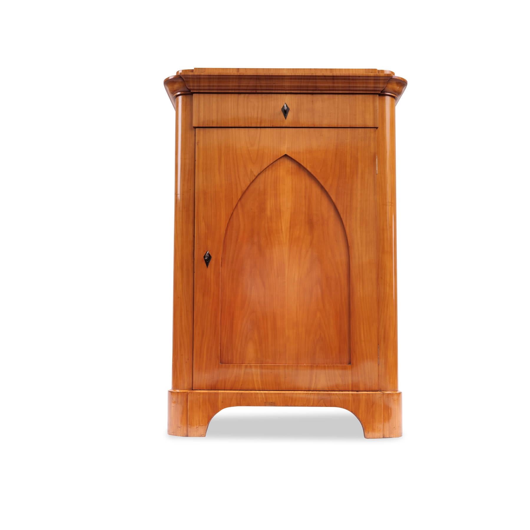 Pillar cabinet / half cabinet, Biedermeier around 1835, cherry veneered, 1 hinged door with neo-Gothic pointed arch panel, 1 drawer, rounded sides, shelves, restored condition, shellac hand polish
Height: 118.5 cm, width: 82 cm, depth 43.5 cm
