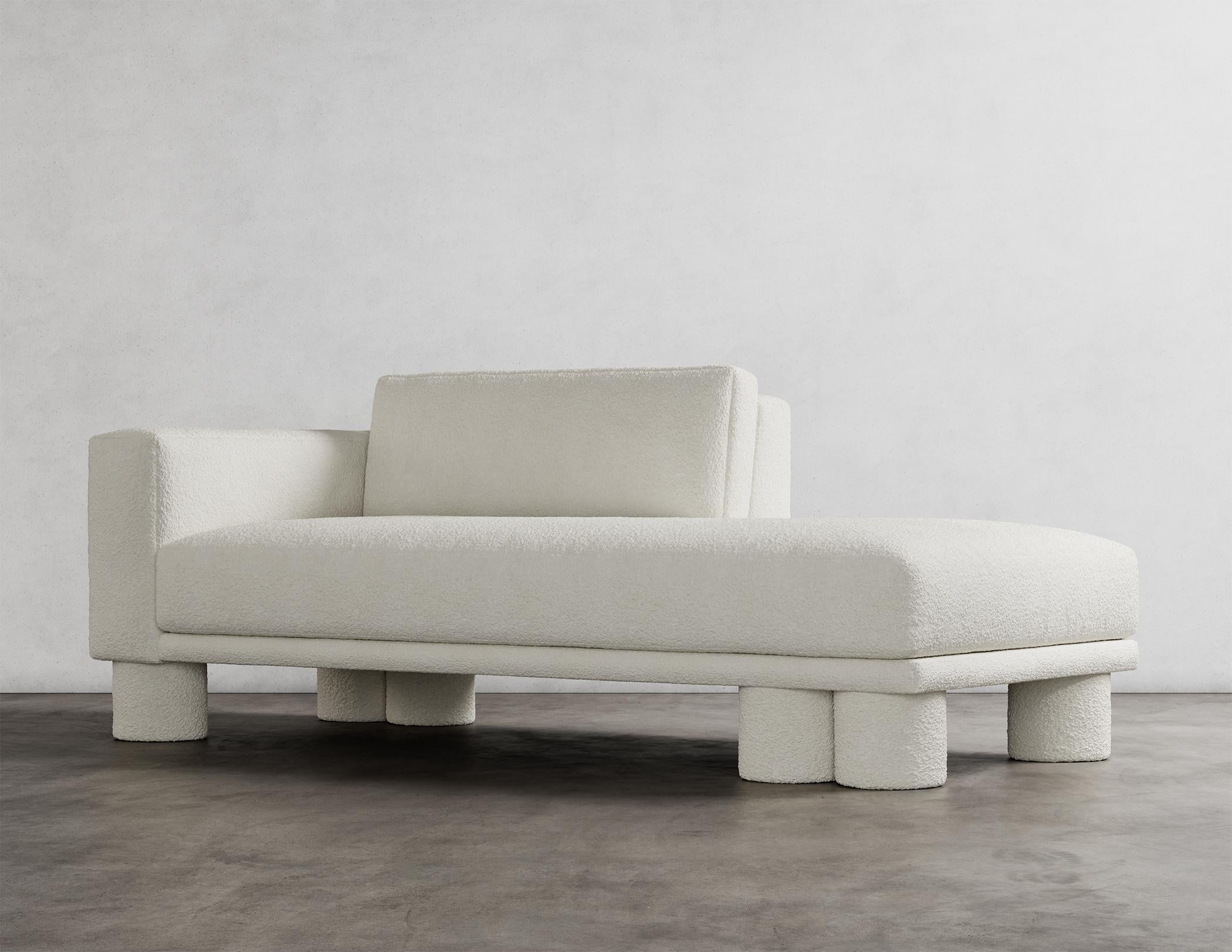 The Pillar Chaise is a stunning piece of furniture with a unique and captivating design. It is characterized by layered, asymmetrical design elements that create a sense of sophistication and simplicity. The deliberate imbalance in these design