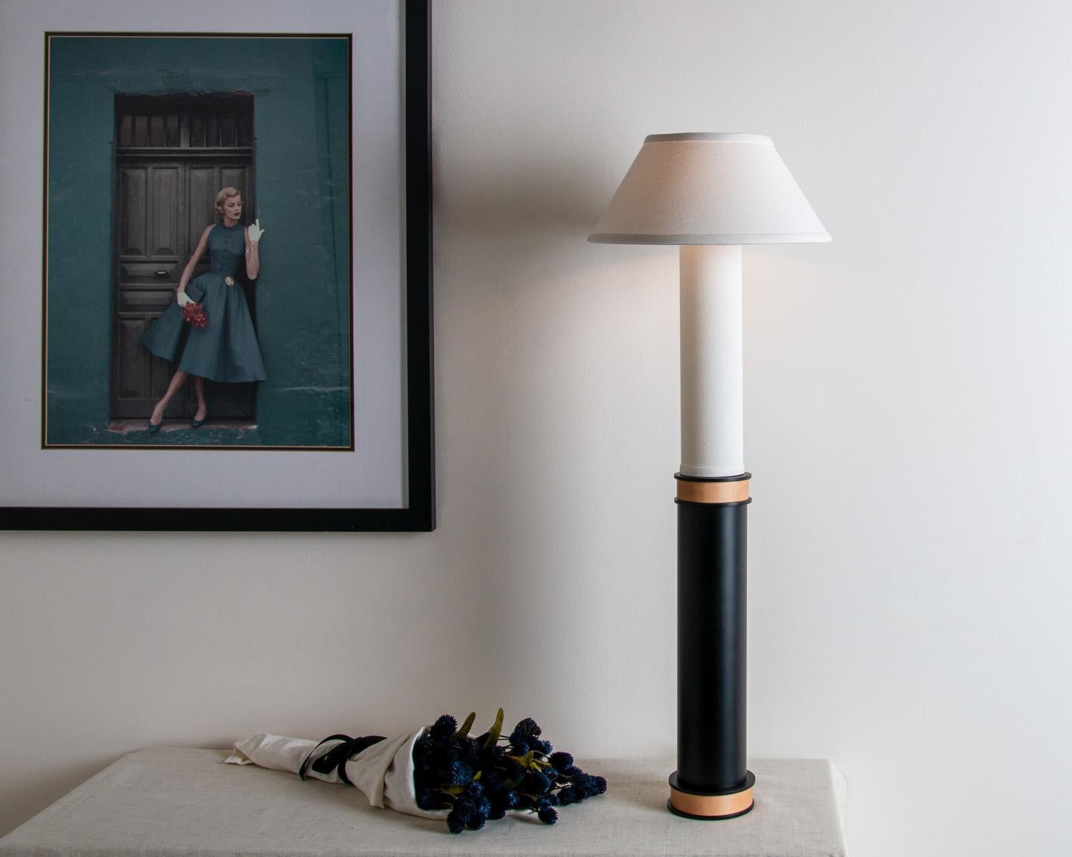 Cette lampe majestueuse présente un contraste spectaculaire de textures et de matériaux. D'une hauteur de près d'un mètre, la lampe à colonne en lin et en acier a une présence prépondérante. Inspirée de la lampe Bouillotte du XVIIIe siècle, cette