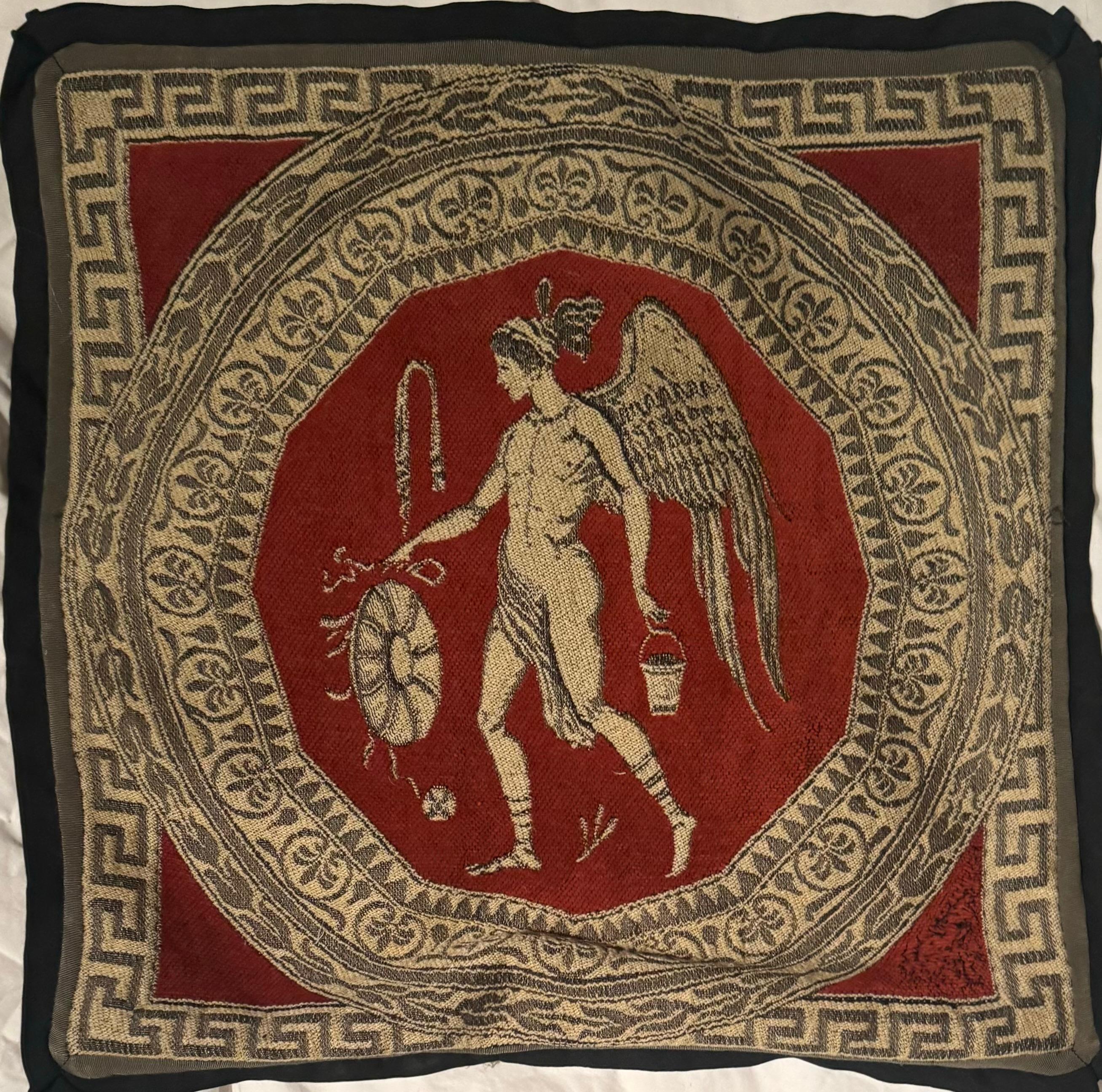 Cet oreiller inhabituel est créé à partir d'une tapisserie du XXe siècle. Le coussin carré est unique et ludique. La tapisserie représente un homme drapé, un dieu ailé, en rouge, crème et gris. La figure classique est entourée de motifs classiques.