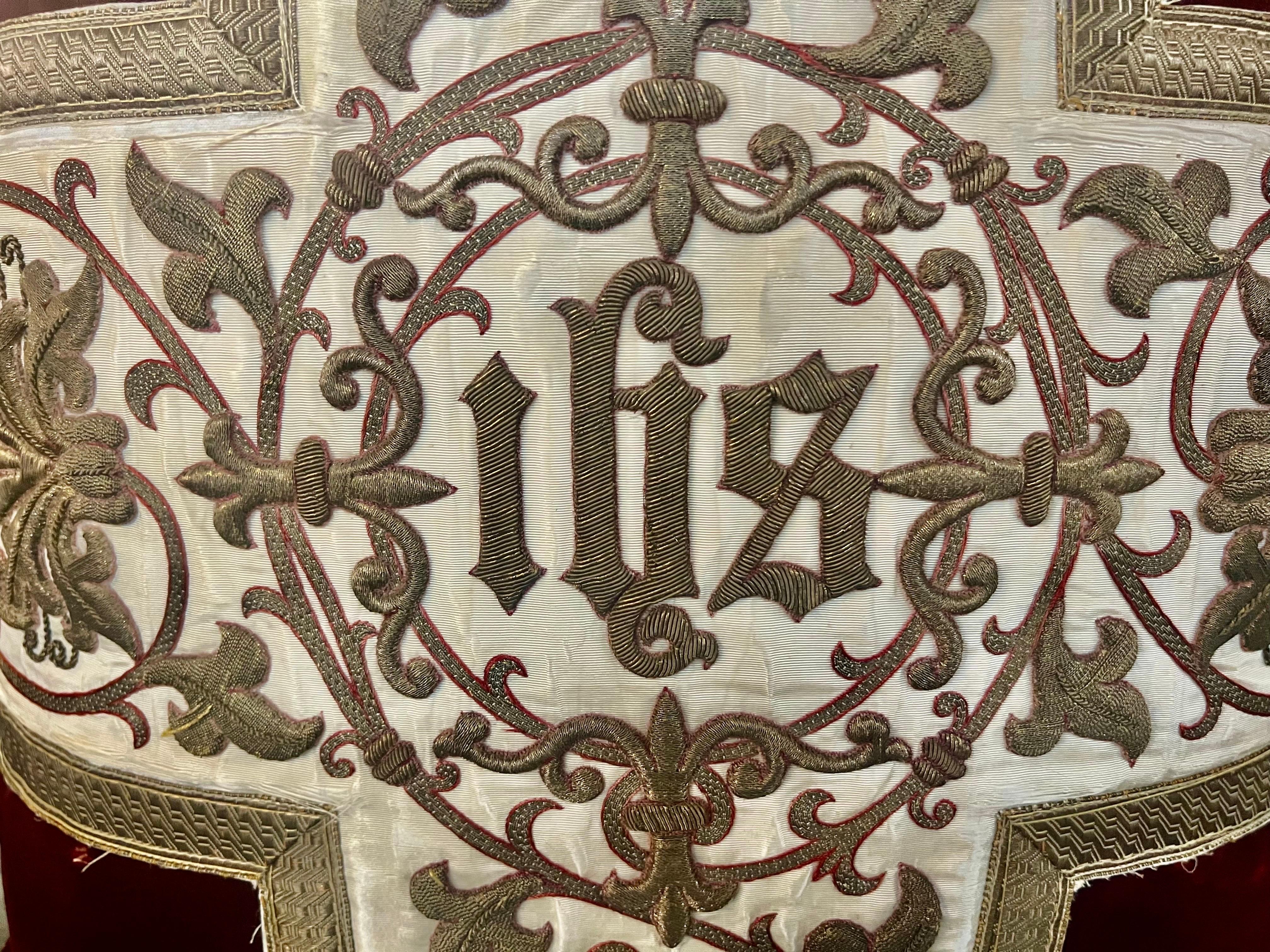 Un royal oreiller en velours de soie rouge incorporant un textile ecclésiastique en soie crème brodé en or métallique du XIXe siècle, comportant les lettres I-H-S, des fleurs de lys, des feuilles d'acanthe enroulées et des fleurs en or métallique