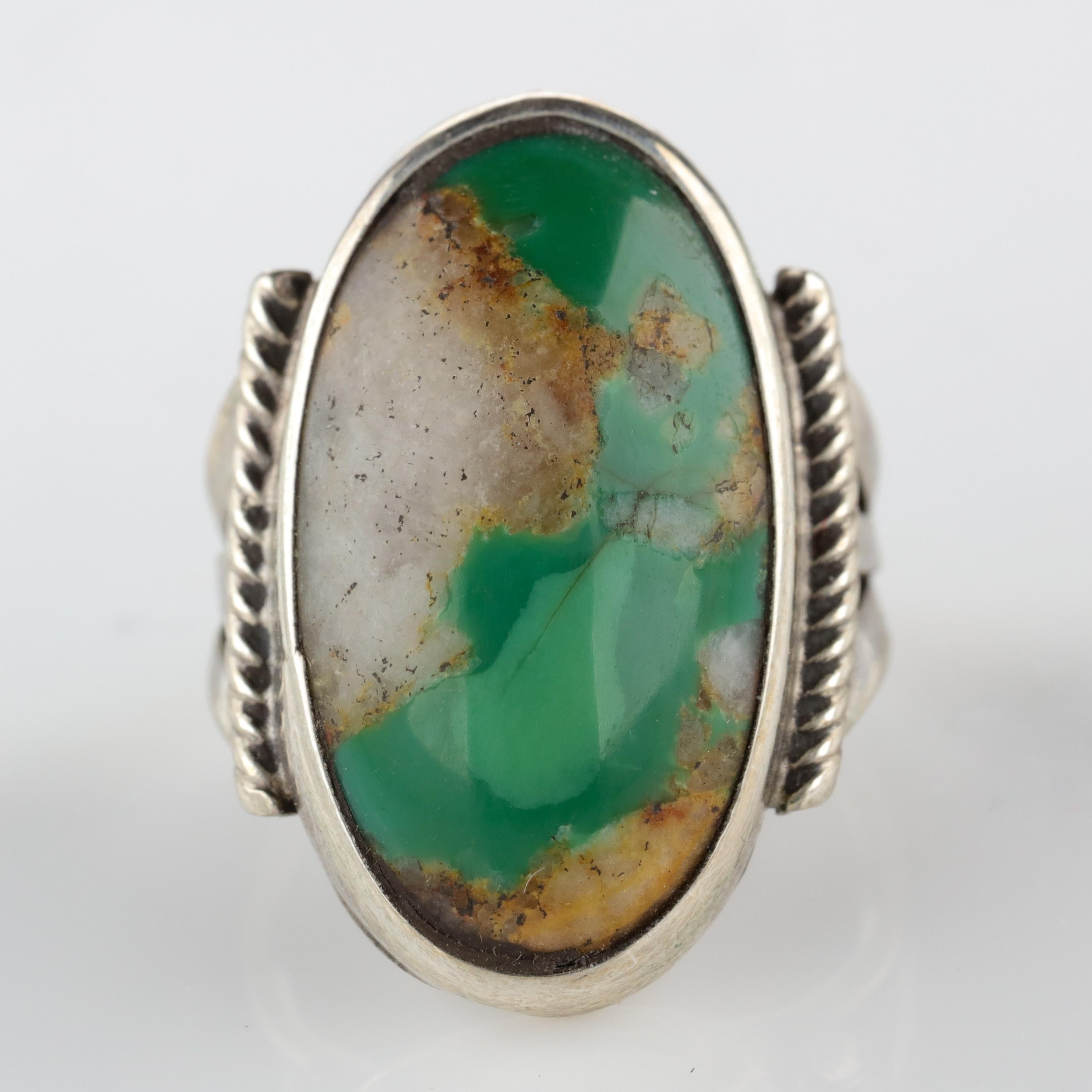 A stunning oblong cabochon of gemmy Pilot Mountain turquoise from the legendary Nevada mine is the focal point of this 1940s-era silver ring. The turquoise is especially stunning because the semi-translucent bluish-green gem is blended with quartz,