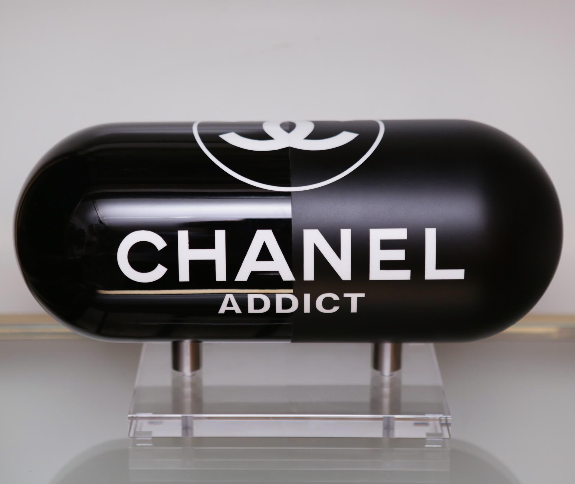 Sculpture Pill Chanel Addict Black in resin
with one side in glossy black finish and 
one side in matt black finish. On plexiglass
acrylic base. Numberded 1/12.
Limited Edition of 12 pieces.