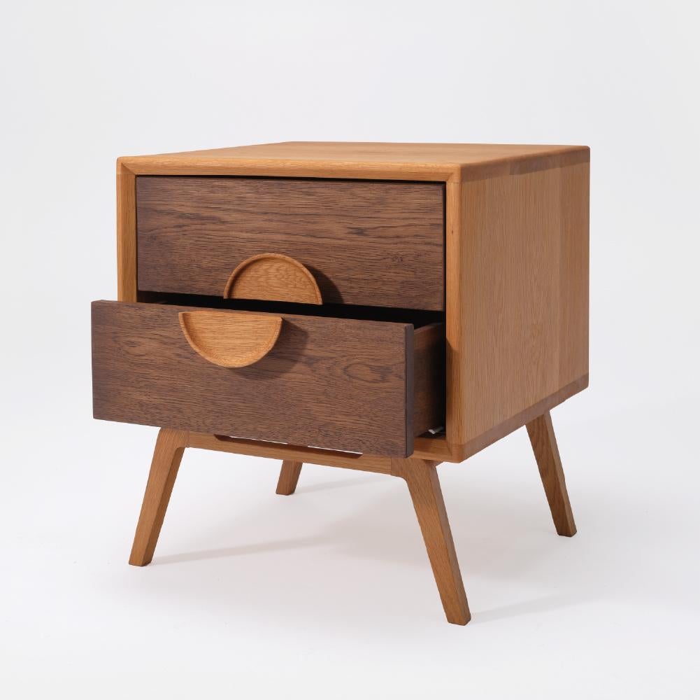 The Pin Nightstand is made entirely from solid oak wood. With its elegant leg design and sturdy frame, it will be a perfect companion for your bedside. Featuring a unique handle design and two spacious drawers, it will become an essential piece in