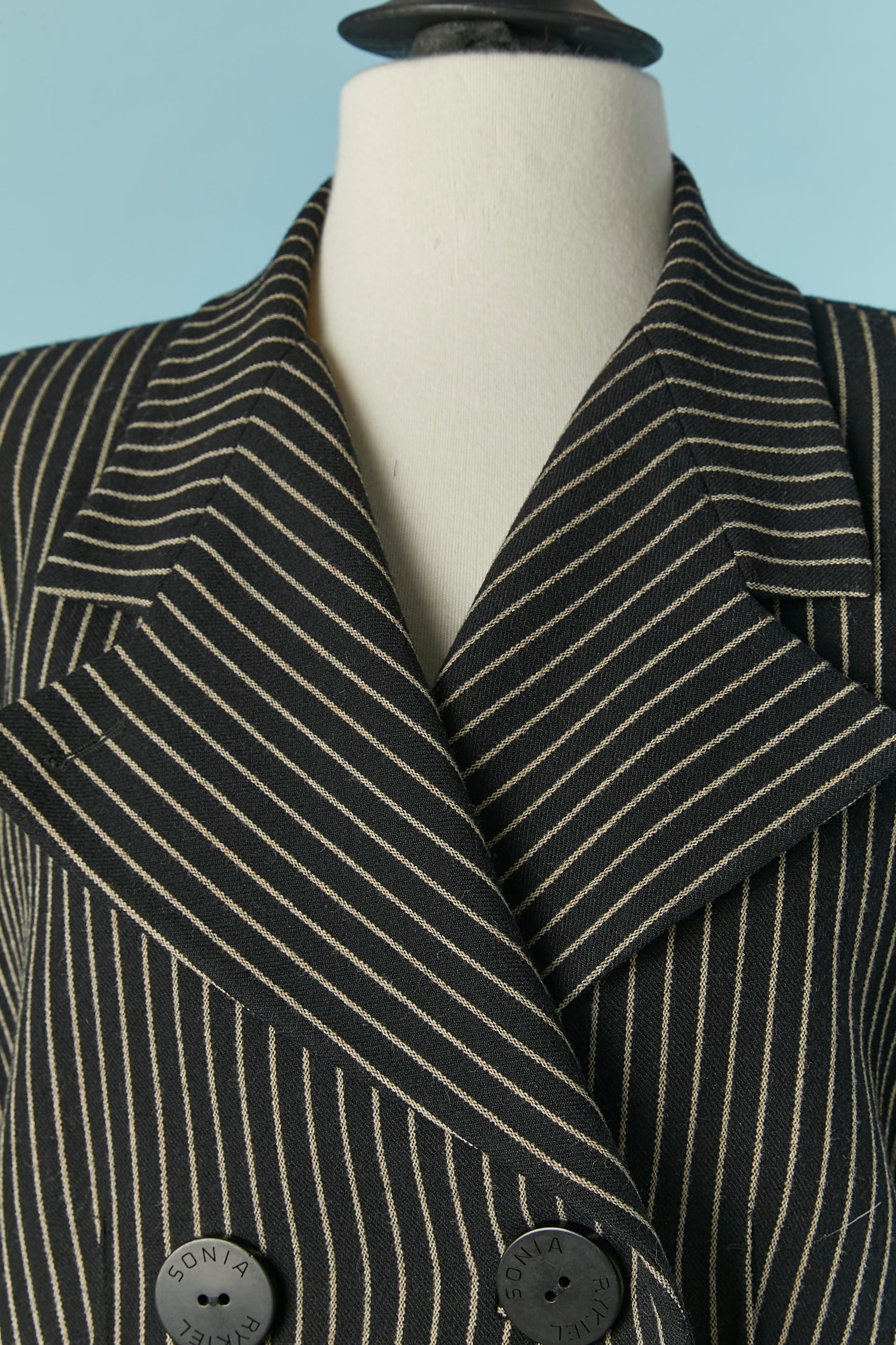 Pin-striped wool skirt suit with double breasted . Main fabric composition: rayon, wool and elastane. Lining: acetate and rayon. 
Branded button and buttonhole closure on the front. Pockets on both side. Shoulder-pad. 
SIZE of the jacket :42 / L