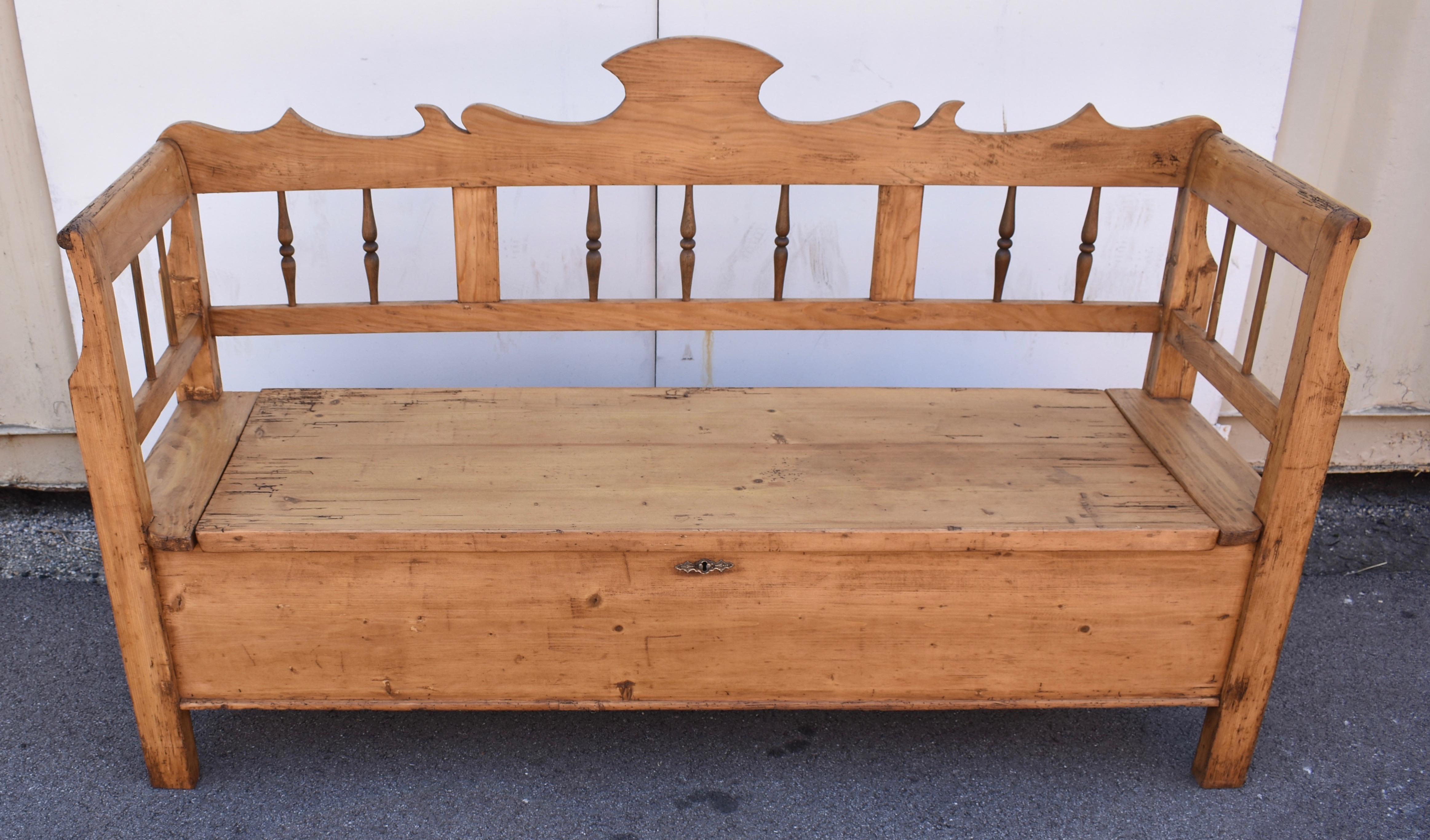 A boldly scalloped and crested top back rail sits atop three frames containing a total of eight hardwood turned spindles.  The straight legs scroll slightly as they morph into the arms, where another frame encloses two round sticks each end.  The