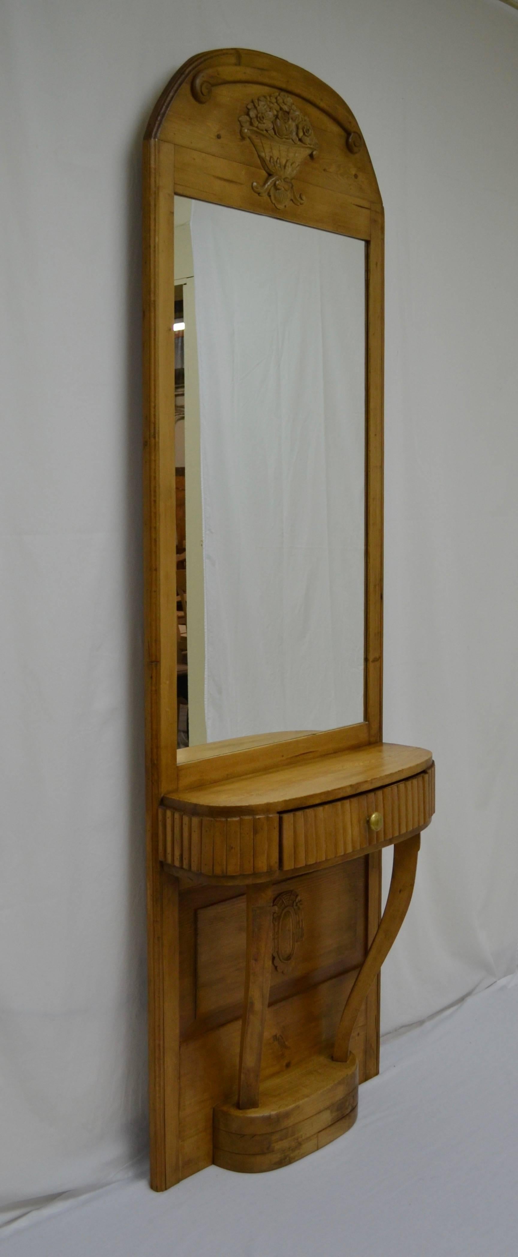 This is a lovely tall and decorative pier or console mirror, ideal for checking your outfit in the hallway before you leave and for putting your keys and gloves away when you get home. The arched top features applied scroll and flower basket