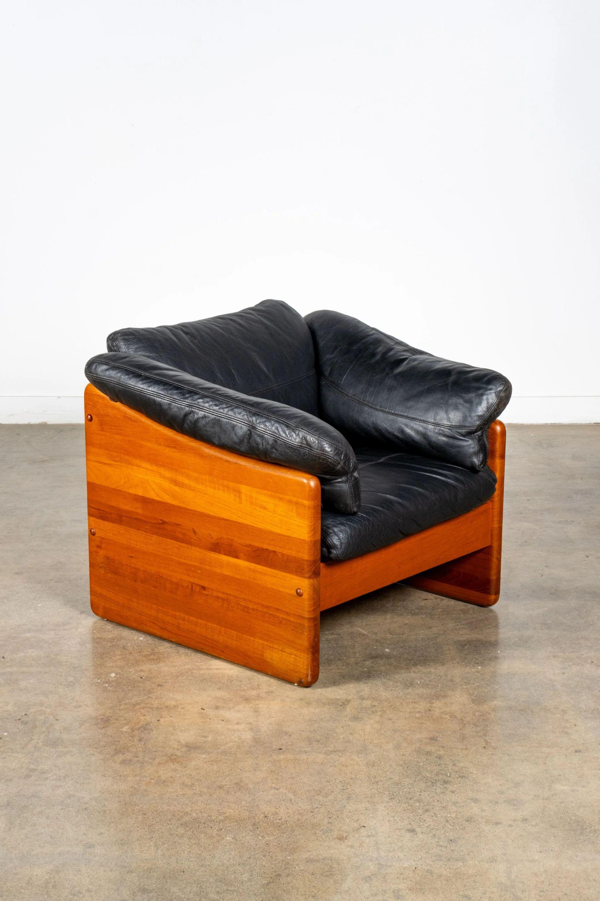 Black leather and glossy pine make for fine companions in inviting lounge chair. The snug fit of the cushions in the frame implies coziness, inviting you to make yourself at home. Smart details add subtle finesse – check out the scalloped edges of
