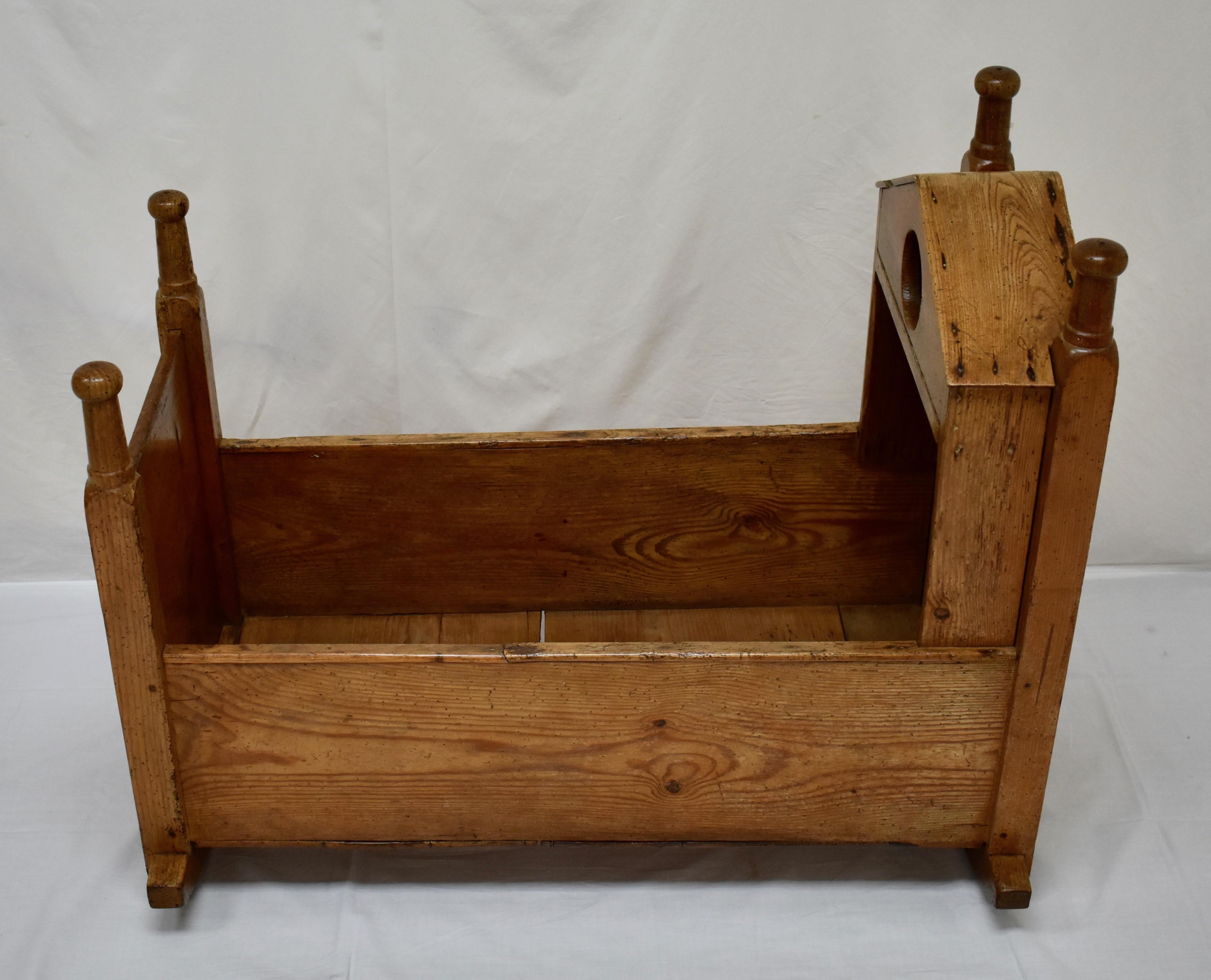 This is a charming, very rustic hooded rocking cradle with an interesting and unusual “bird house” with a circular opening, built into the shallow hood, presumably to store small items; perhaps toys or other distractions. The sides and bottom are