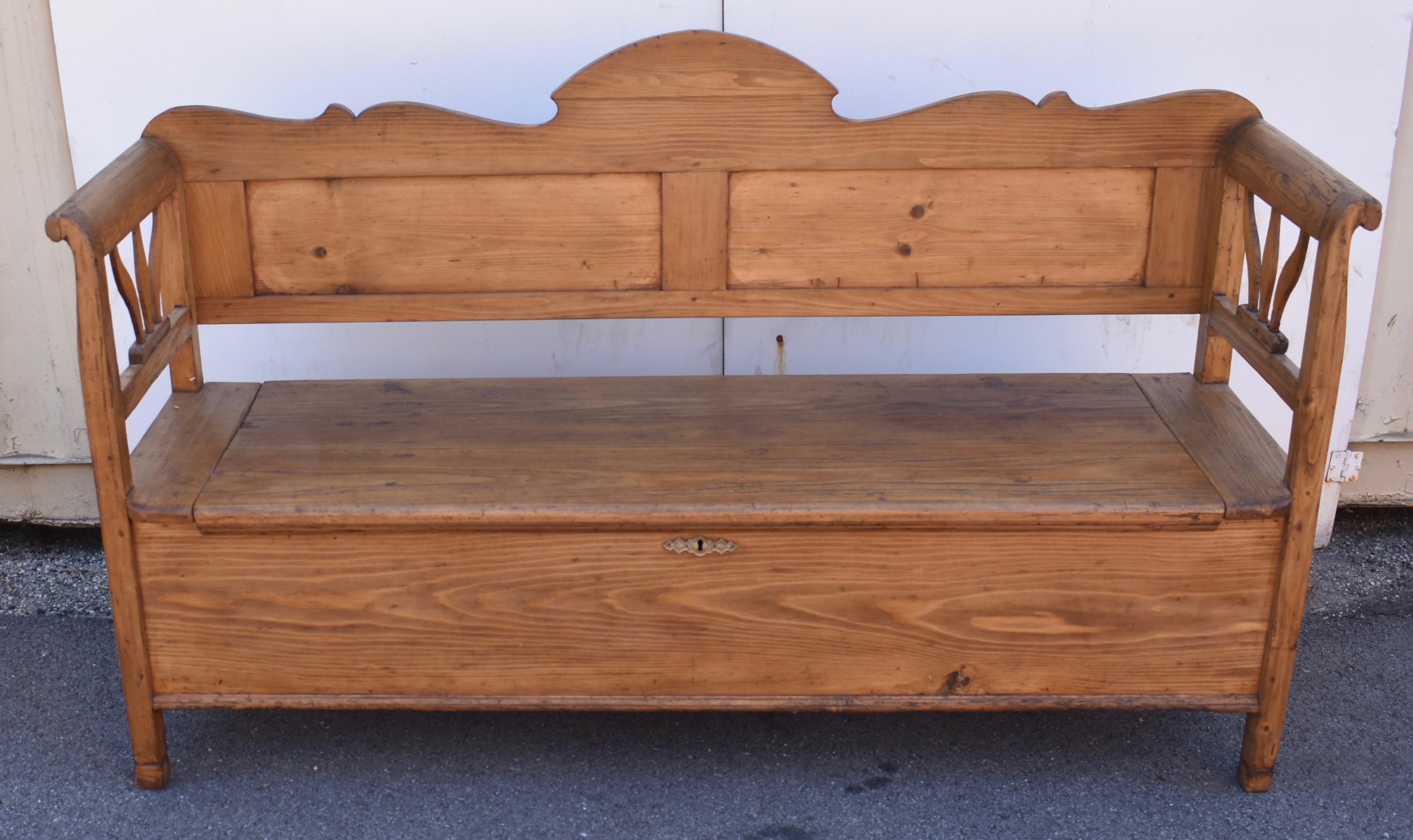 This handsome Box Bench has a boldly scalloped and crested top rail, which frames rwo rectangular flat panels.  The four stiles that form the integral arms/legs of the piece are of oak, straight and then scrolled at the top.  The top and bottom side