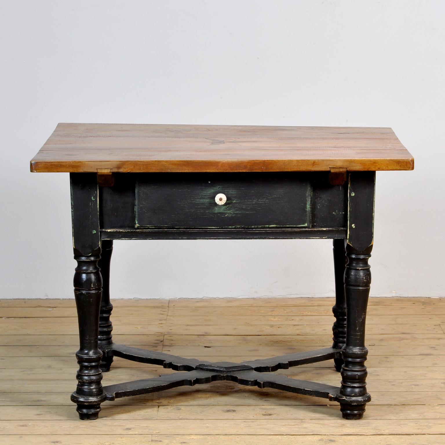 Tisch aus den 1920er Jahren mit einer Schublade. Der Tisch ist aus Kiefernholz mit einer Platte aus Eichenholz gefertigt. Die Oberseite ist mit einer Sternintarsie versehen.
