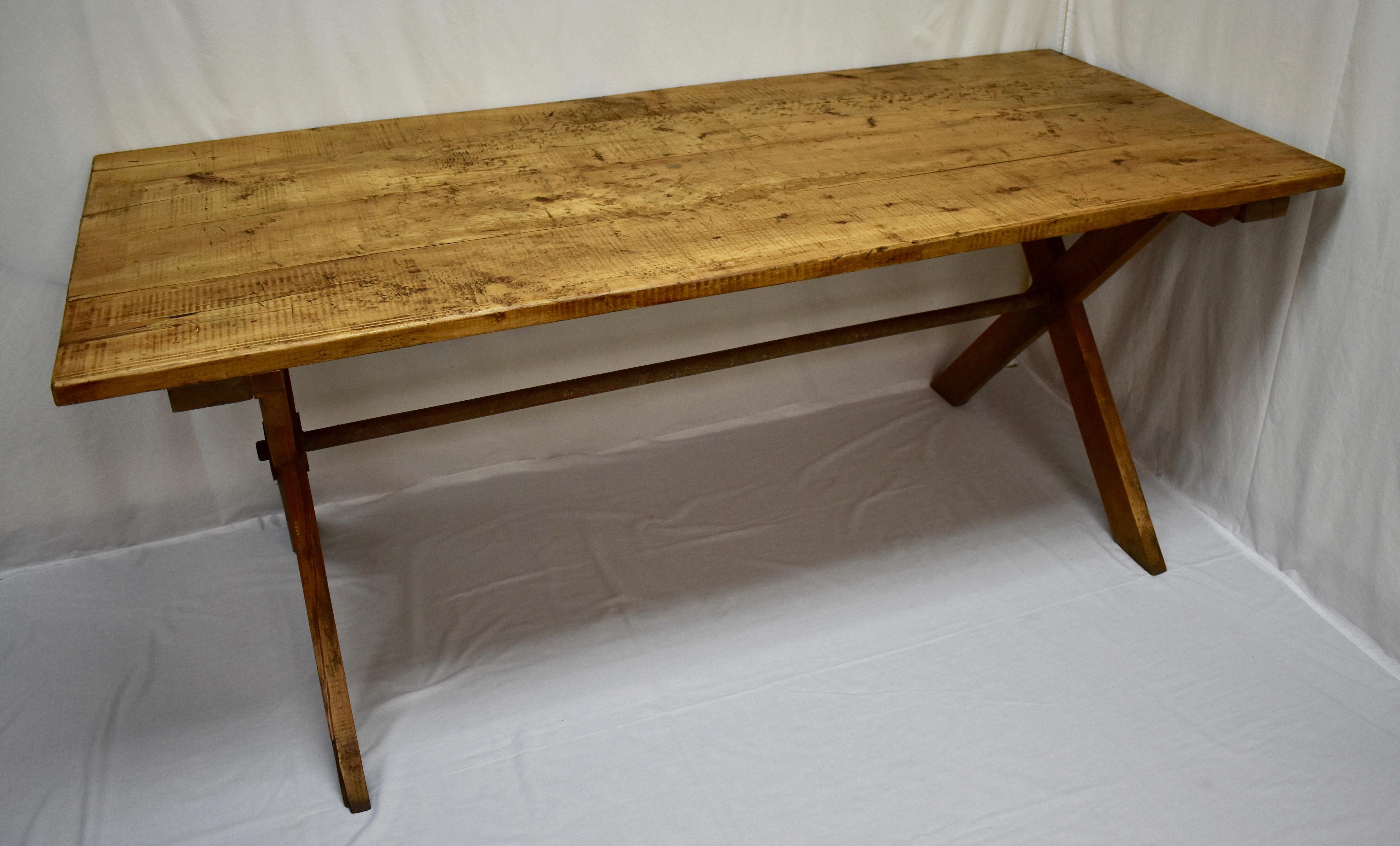 This is a beautifully worn “X” base trestle table, perfect for a country kitchen or dining room. The four board pine top, 1.25” thick, is scratched, chipped and gnarled and shows great character, developed over decades of purposeful use. It is
