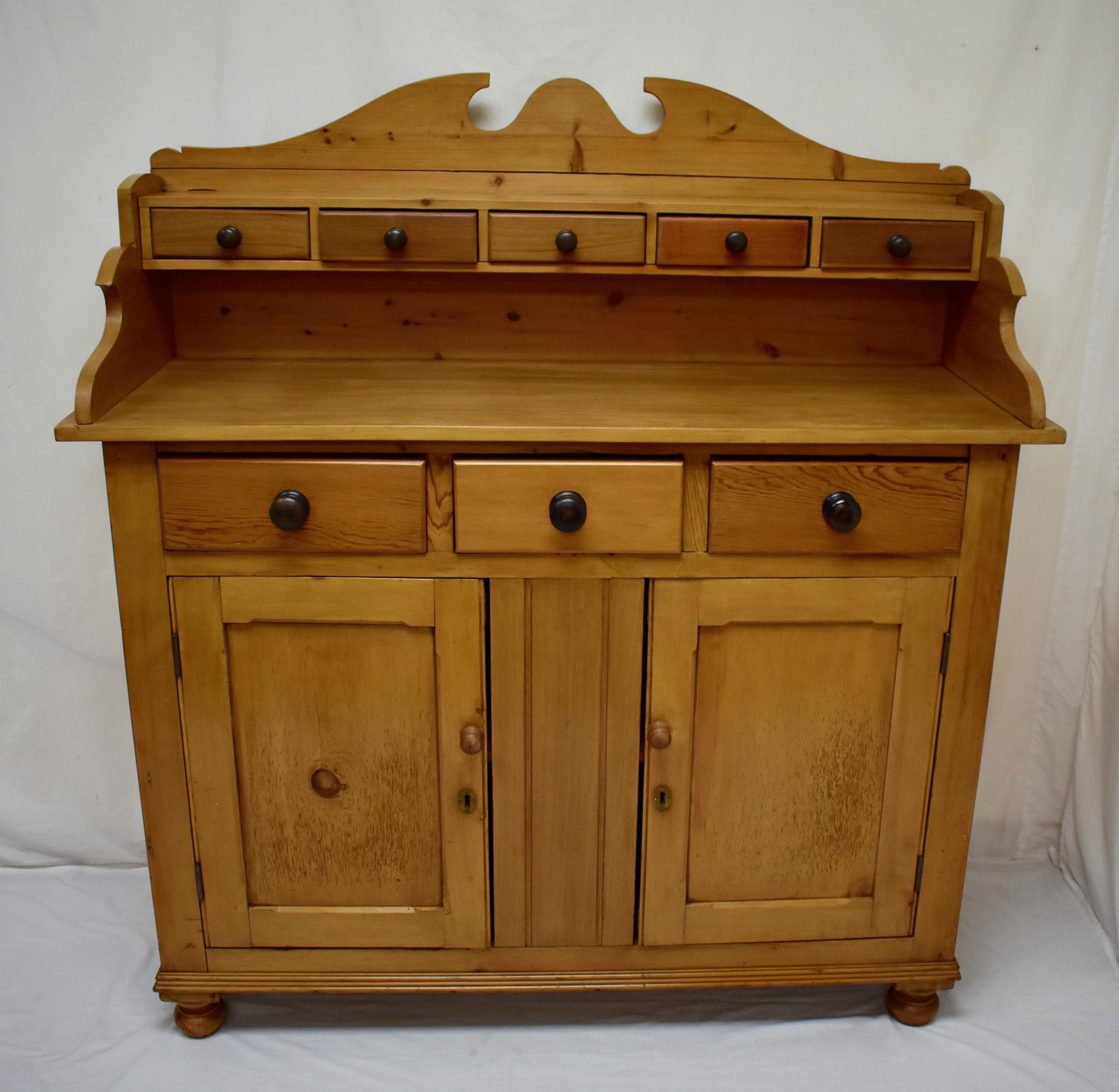 This handsome Scottish dresser features a pine gallery with a high scalloped back, housing five handcut dovetailed spice drawers, with drawer fronts and bottoms of mixed wood species. The sides are of pine “tongue and groove” boards, The base has a
