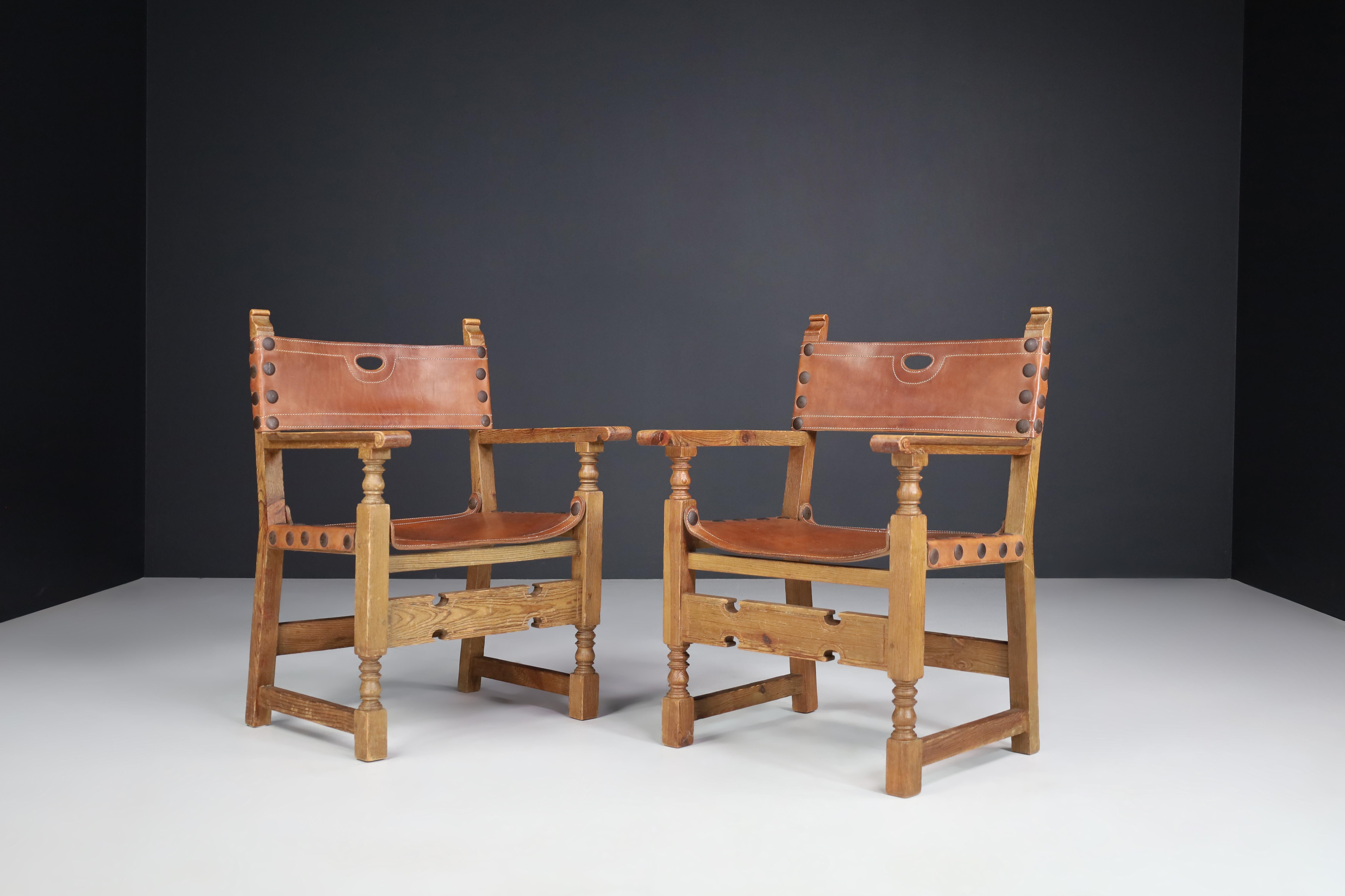 Pine and saddle leather arm chairs, France 1940s.

A striking pair of French armchairs in pinewood dating from the 1940s with original saddle leather seats, backrest, and large domed metal studs. Standing on rectangular legs joined by a broad