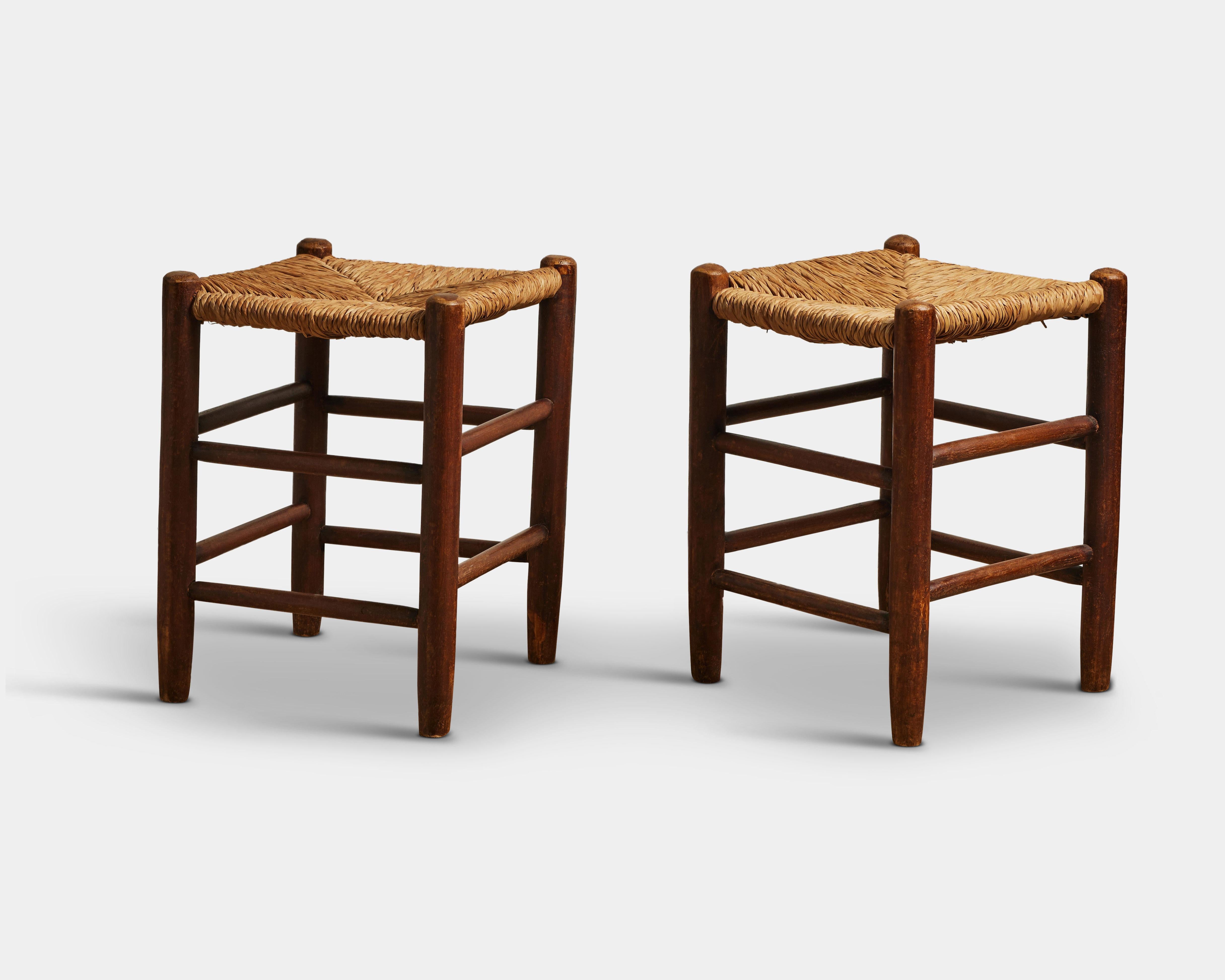 Refined, rustic stools with woven rush tops and supports running between the legs, in the manner of Charlotte Perriand.