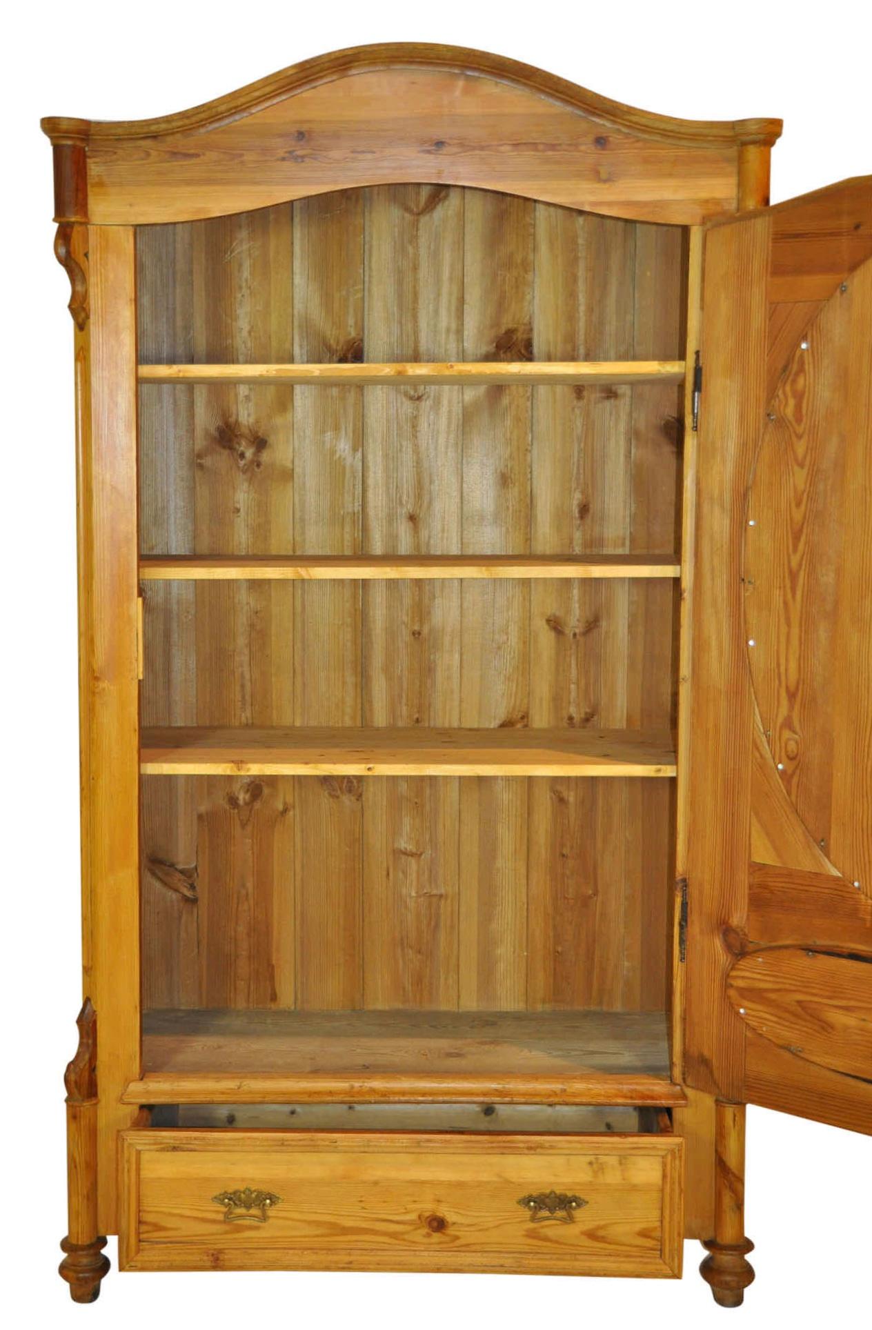 The soft lines of ovals and aches are featured in this pine armoire with its bonnet top and arched door with recessed ovals. The armoire has three removable shelves and a lower drawer.
   