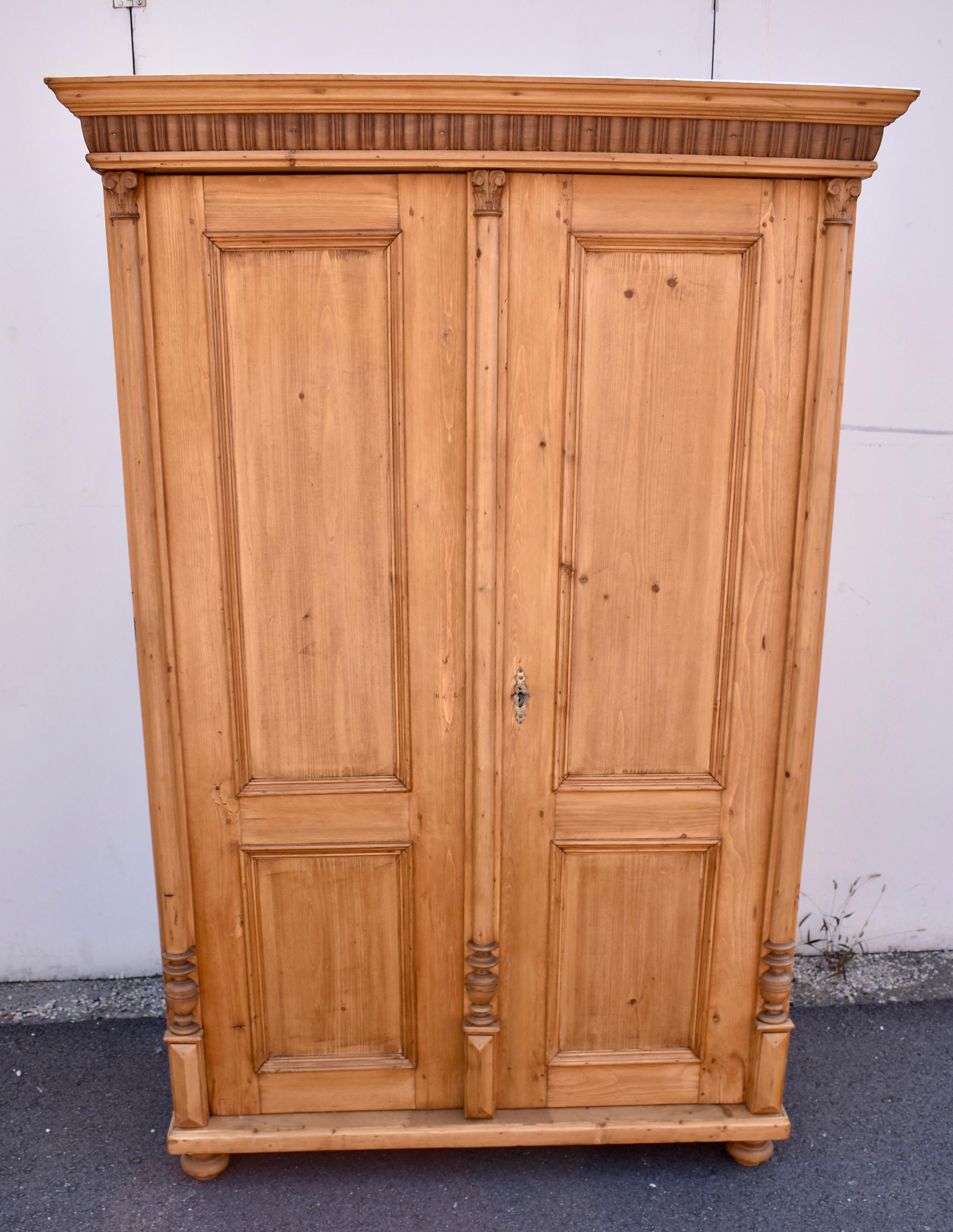 The crown of this good-looking two door armoire is made more attractive by the contrast between the pine crown molding and the hardwood gadrooned frieze beneath it.  Each door has a long flat panel with a much shorter one beneath it.  The front