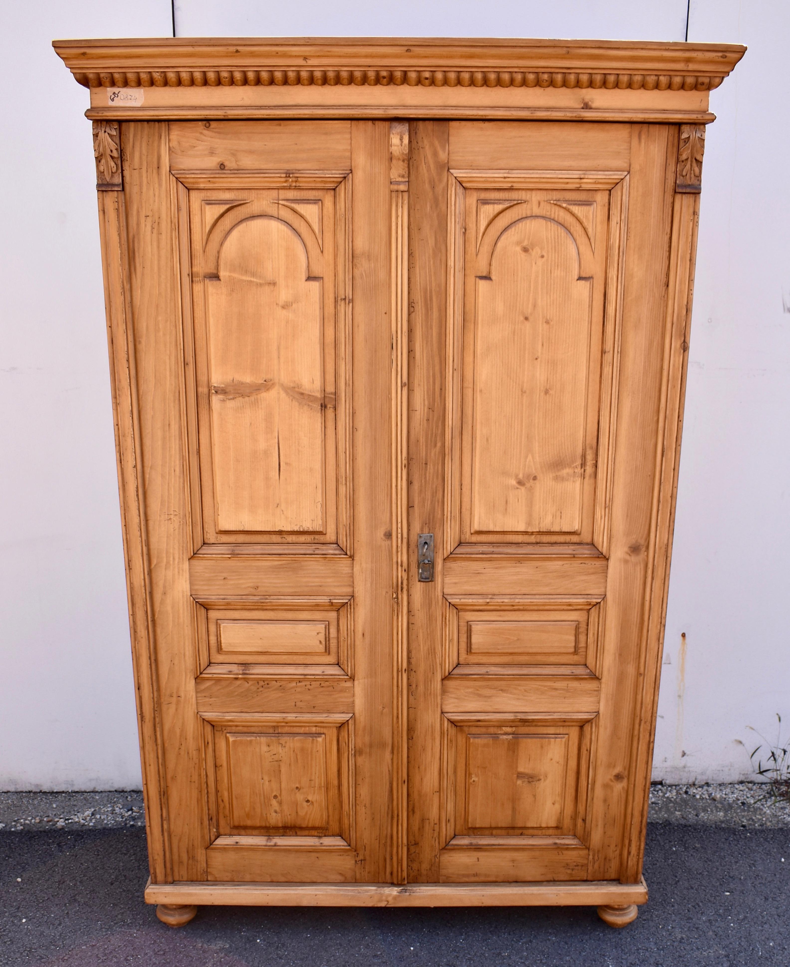This compact little armoire has a lot going on.  The ogee crown molding is bold and attractive and has a strip of large bead molding beneath.  Each door has three raised panels.  The top one is arched with triangular appliqués in the upper corners;